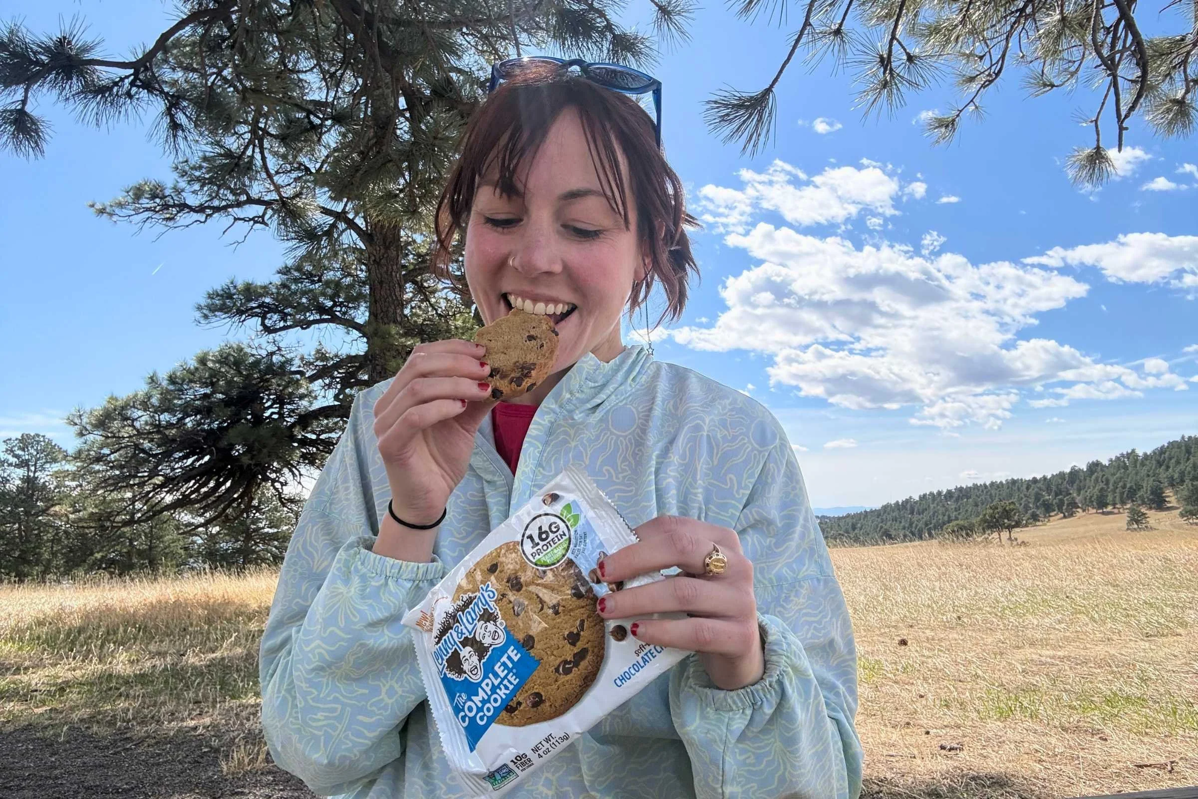 treeline writer becca downs eating a lenny & larry’s complete cookie at a campground