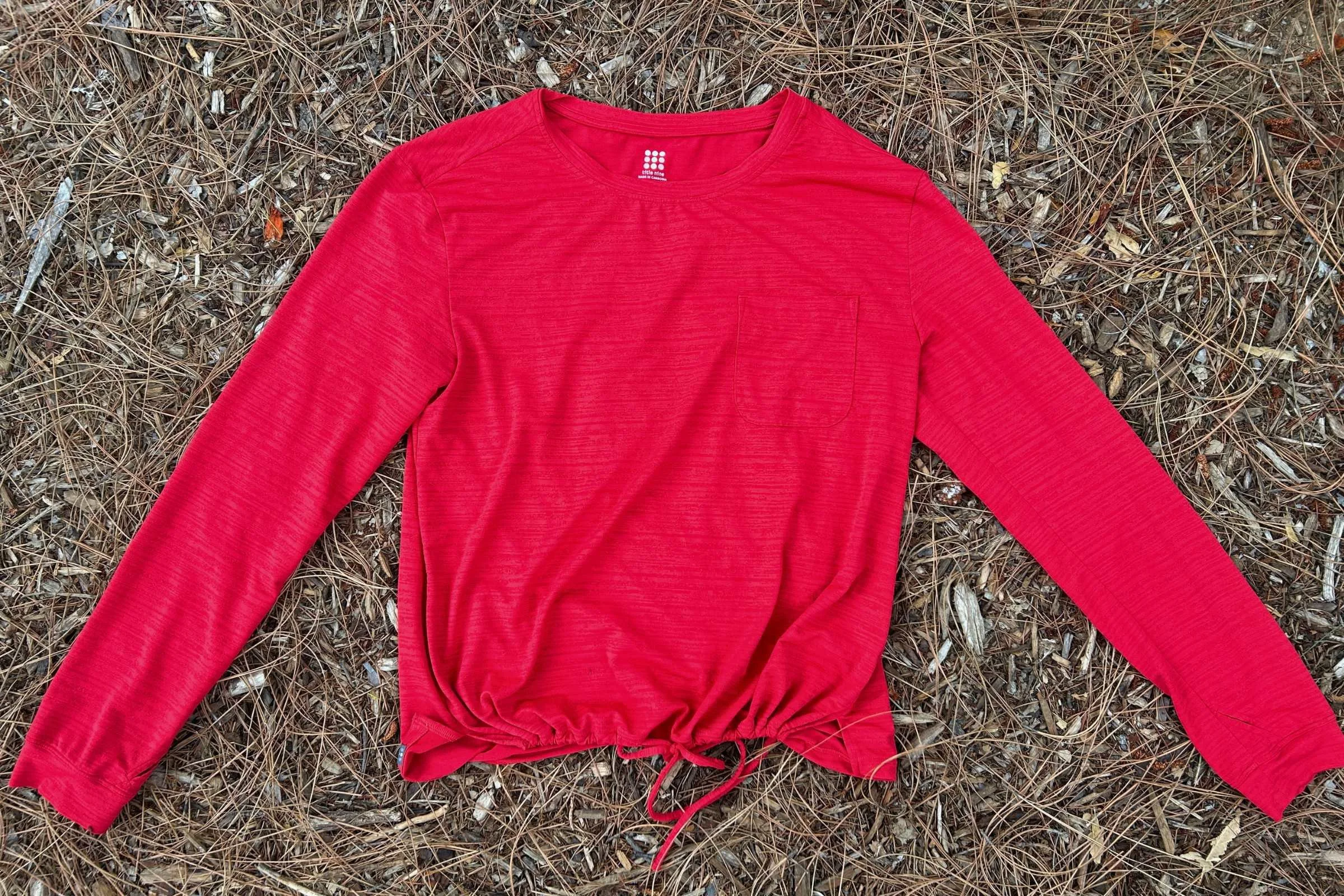 Flatlay photo of the Title Nine Upland LS Sun Shirt on a pine needle forest floor