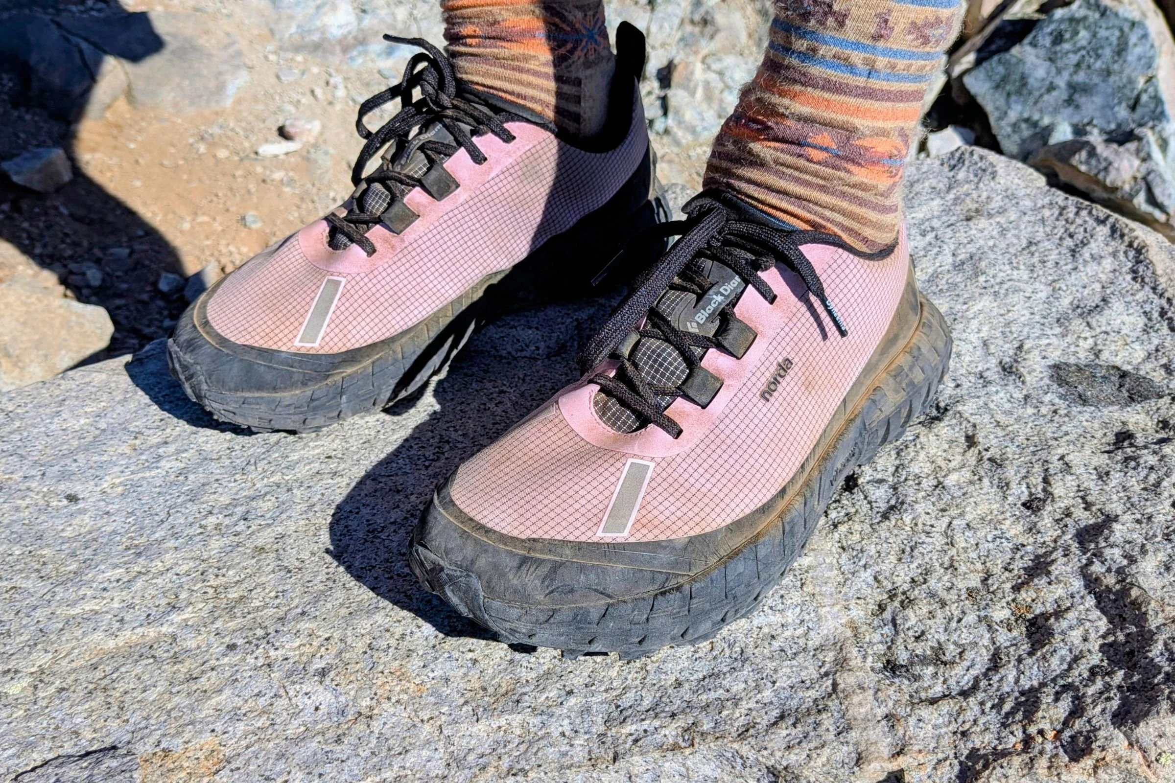 Person wearing pink Norda 000 Trail Running Shoes standing on a rock.