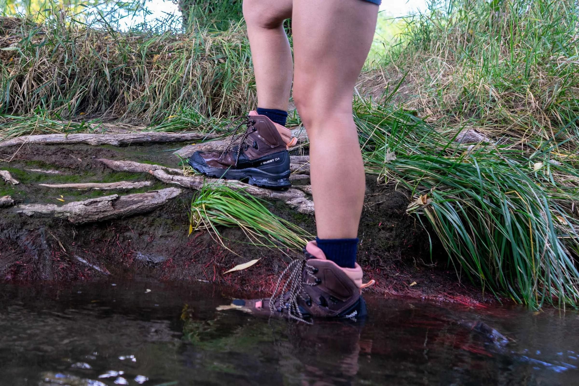 Hiker climbs creek bank wearing in the Salomon Quest 4 GTX hiking boots