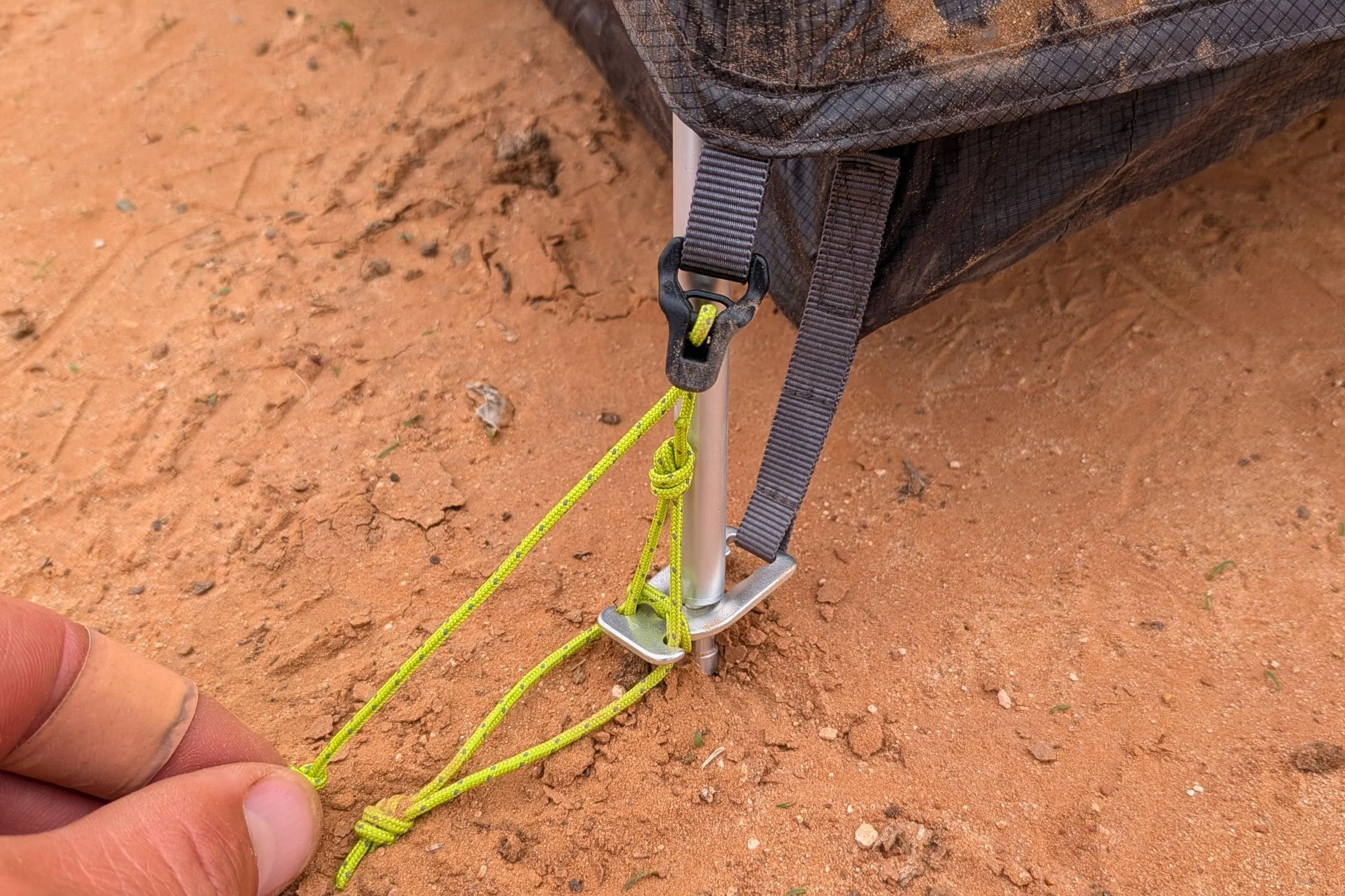 A hand adjusts the corner guyline beside a pole attachment on Gossamer Gear The Free.