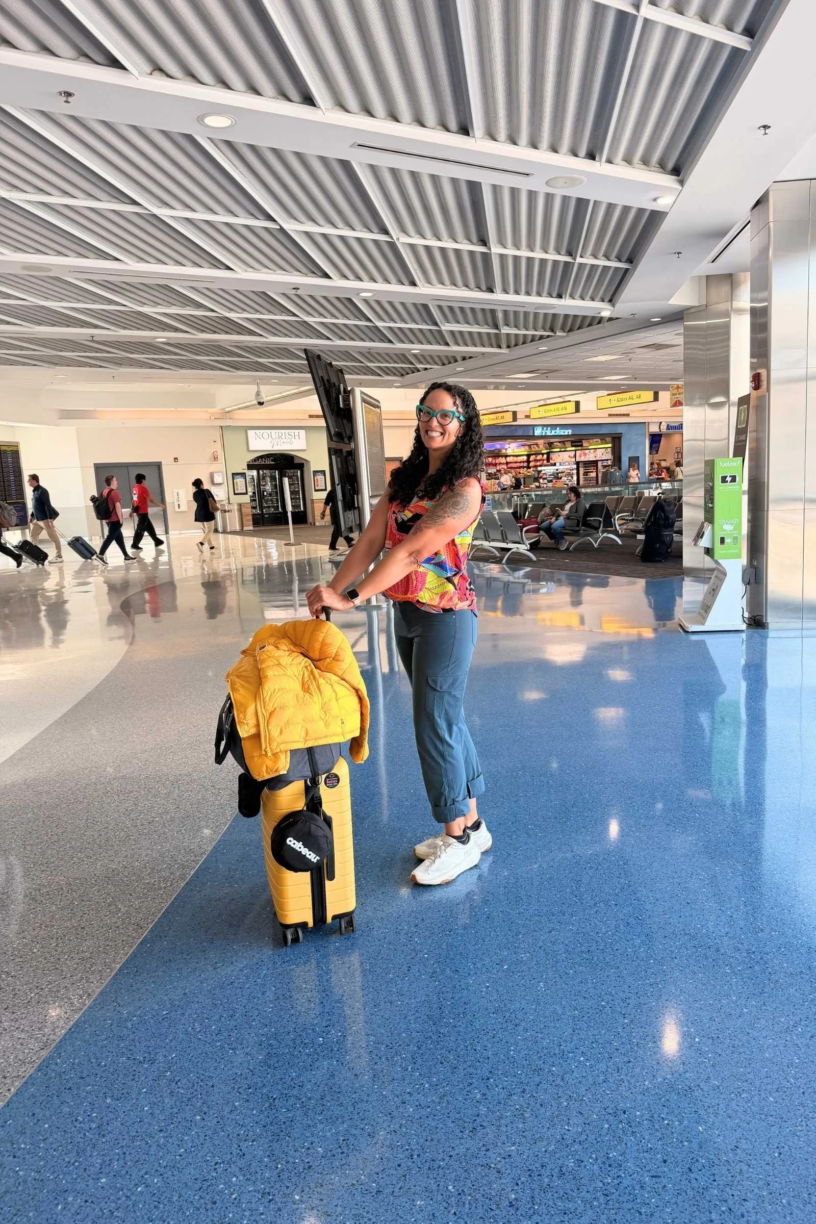 Woman managing luggage while wearing Kuhl Freeflex Roll Up Pant travel pants in an airport
