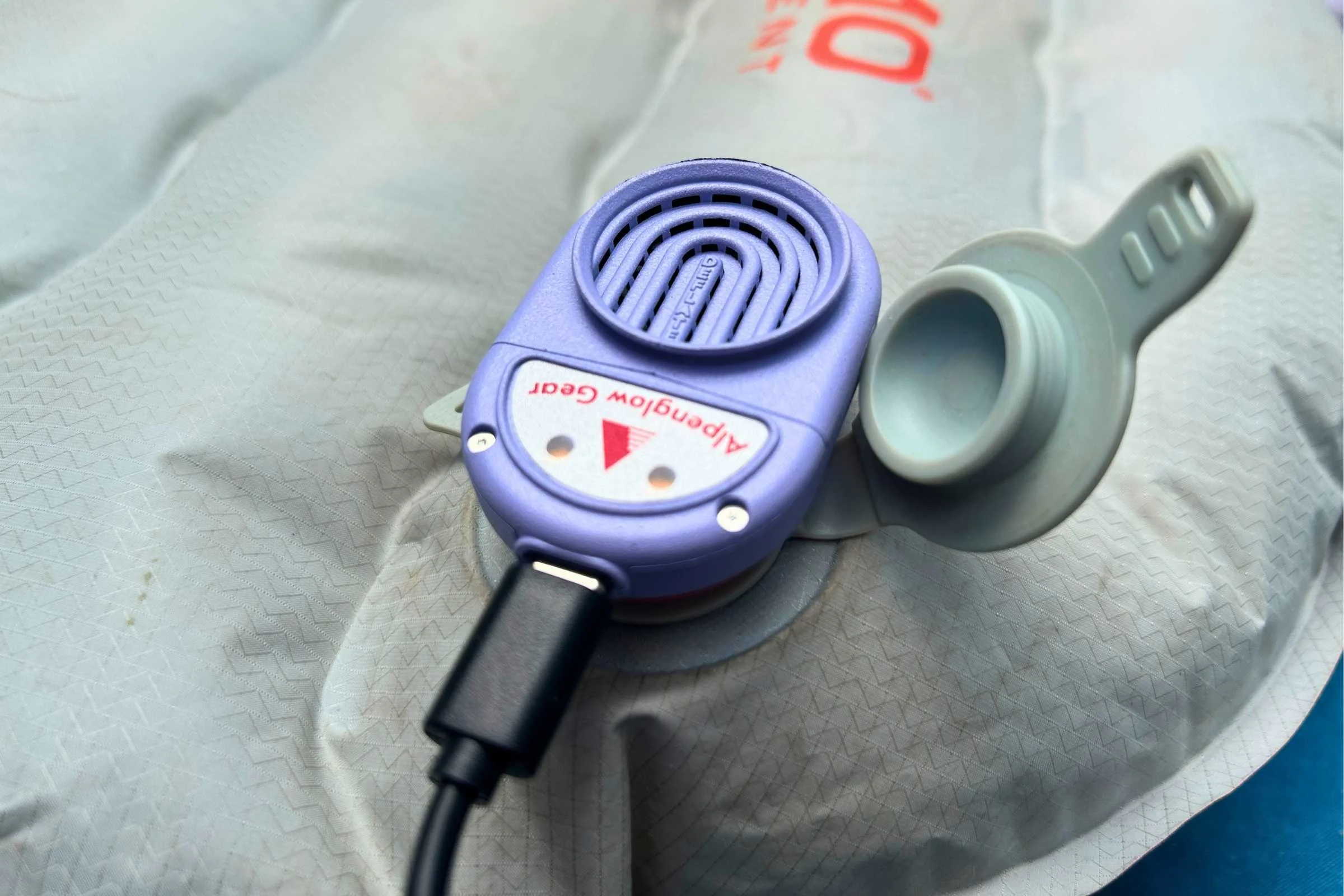 Alpenblow Lux small device plugged into a pillow in a camping gear close-up.
