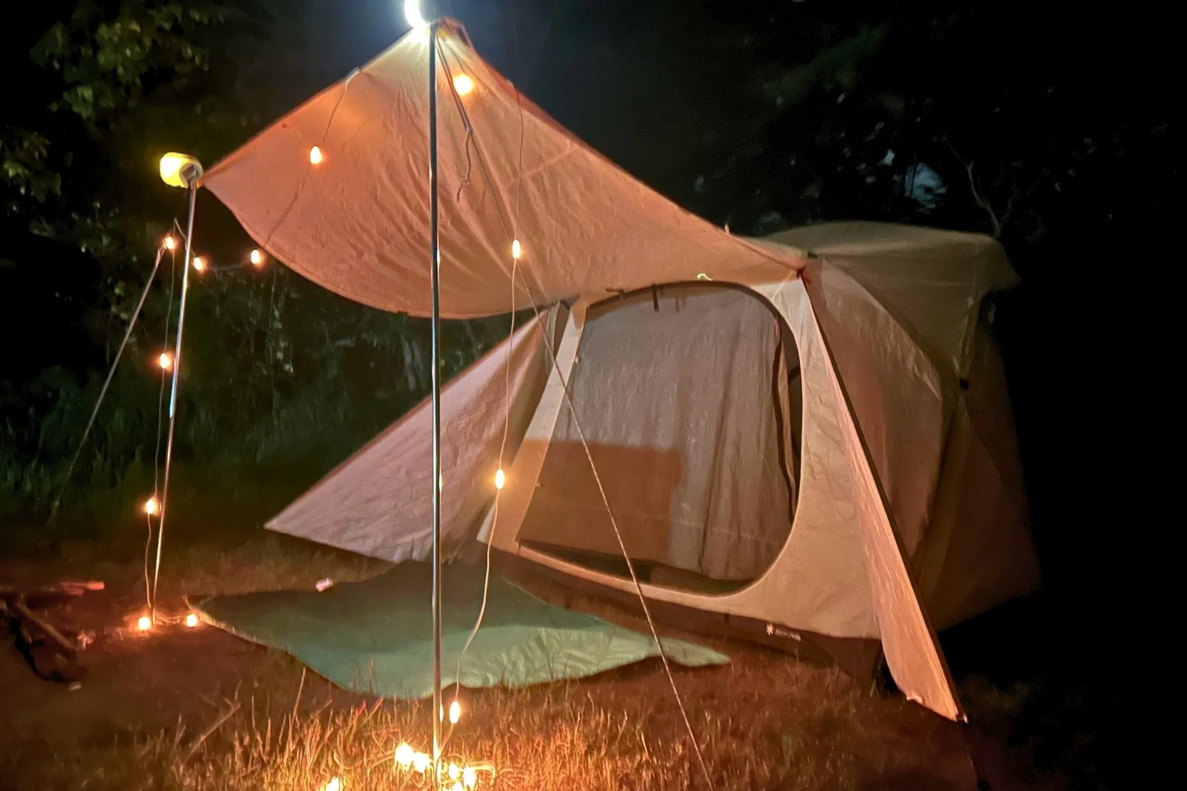 BioLite Luci 44' Solar String Lights hang around a camping tent and its awning at night.