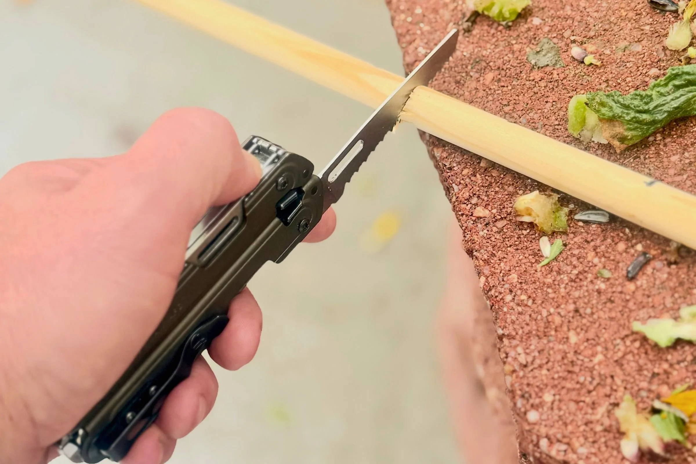 Using the Leatherman ARC’s saw to cut a wooden dowel.