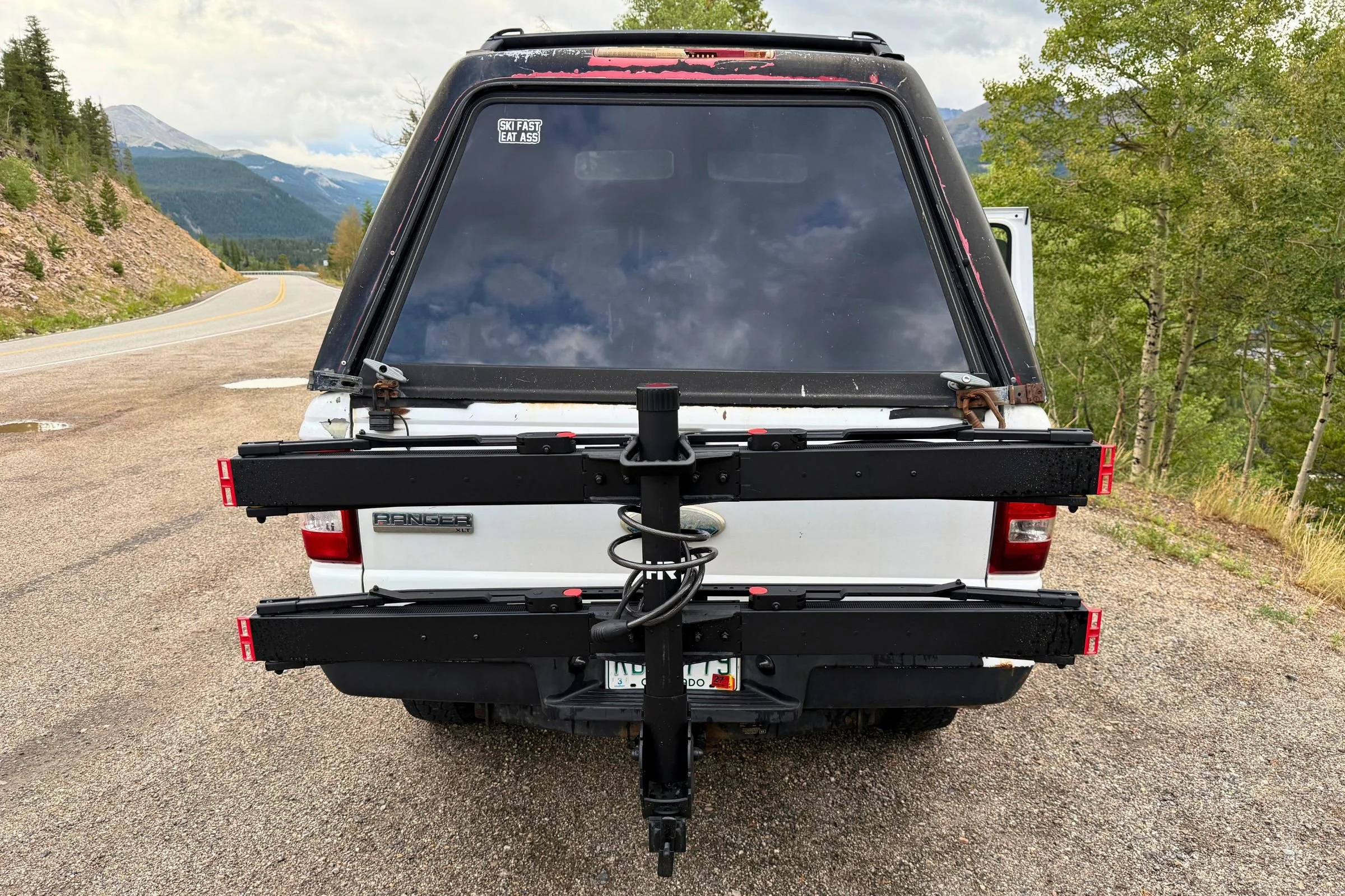 A white truck with an empty Hollywood Racks CrossTrack Hitch Bike Rack in the folded position.