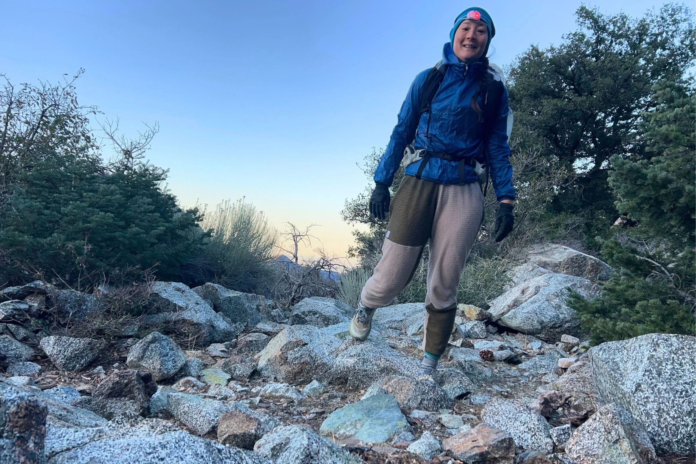 The author wearing the Petzl Swift LT headlamp in red light mode during an early-morning start with the sun coming up in the background.