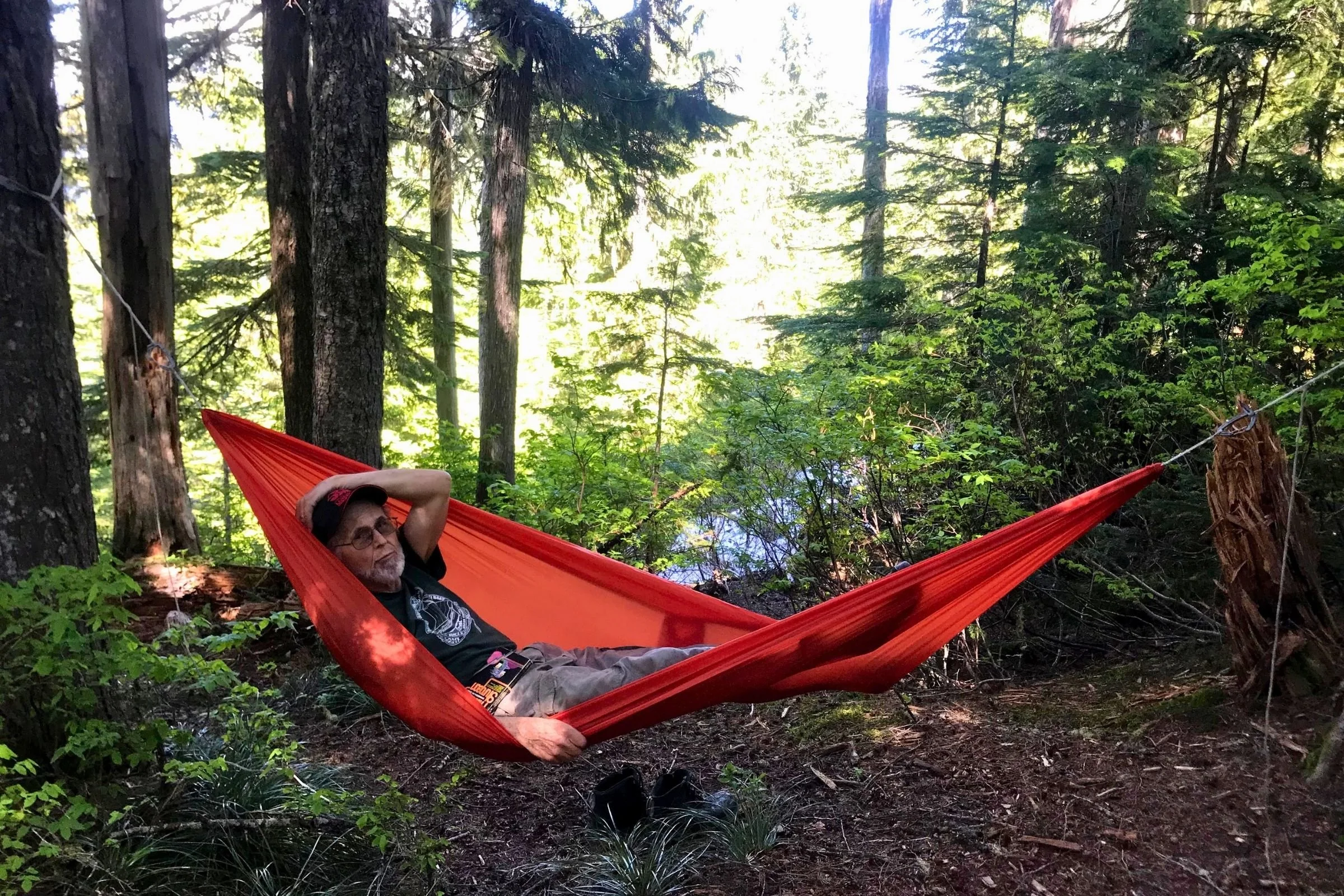 Here a man relaxes in an ENO Sub6 Ultralight Hammock at Granite Lake. Ensure that the hammock straps are securely attached to trees or anchor points and distribute the weight evenly for a stable and safe hang.