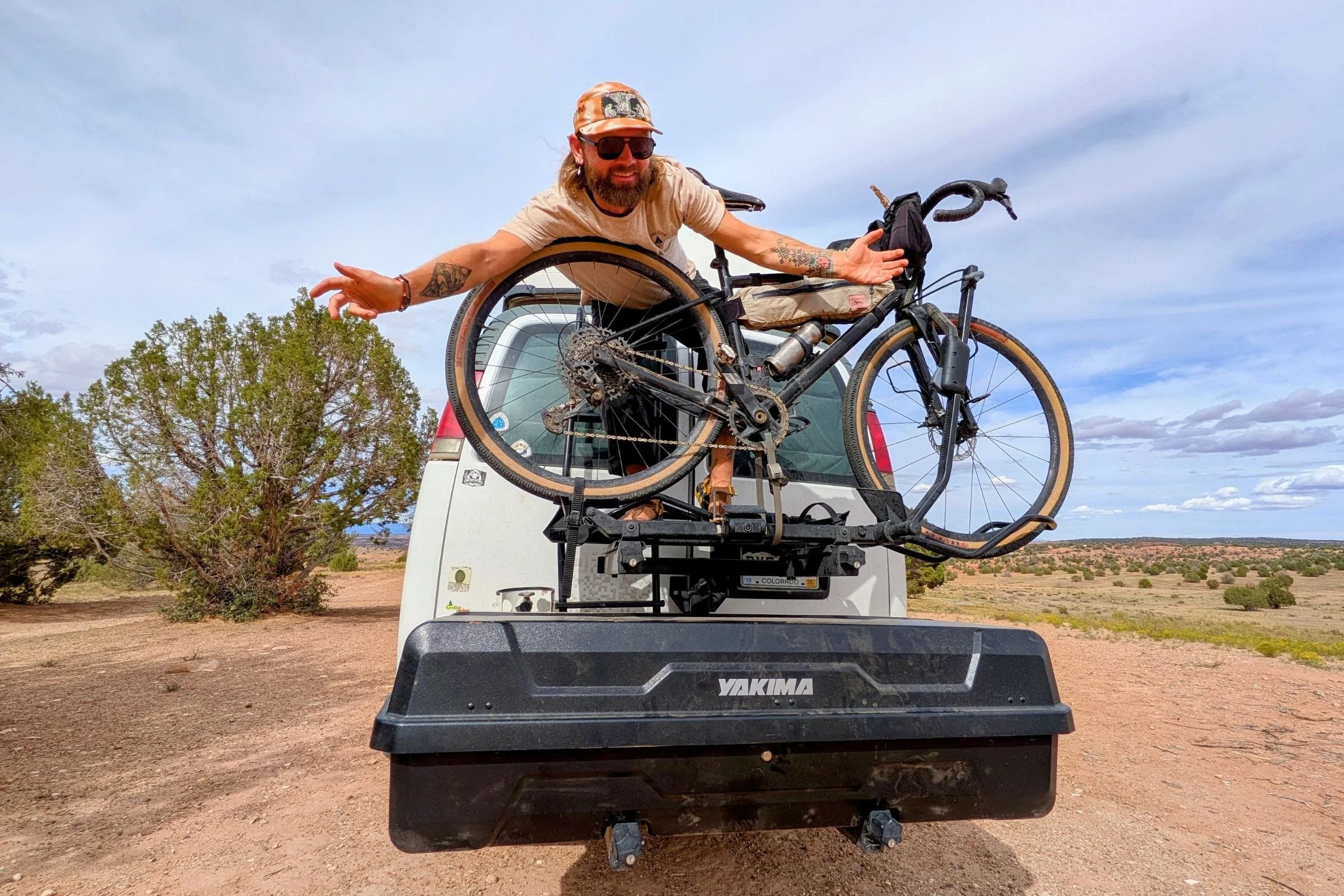 Author Sam Schild leaning over two bicycles mounted above a Yakima EXO GearLocker behind a van
