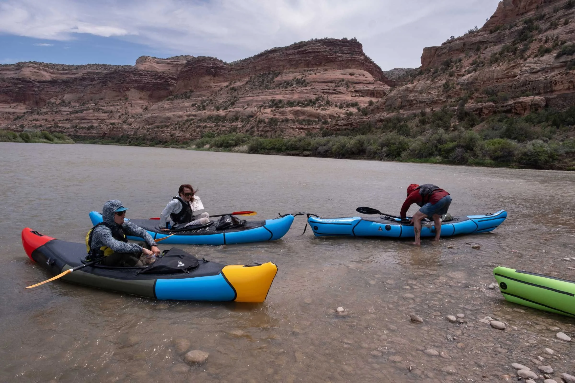 Paddlers sit on the river in various test rafts