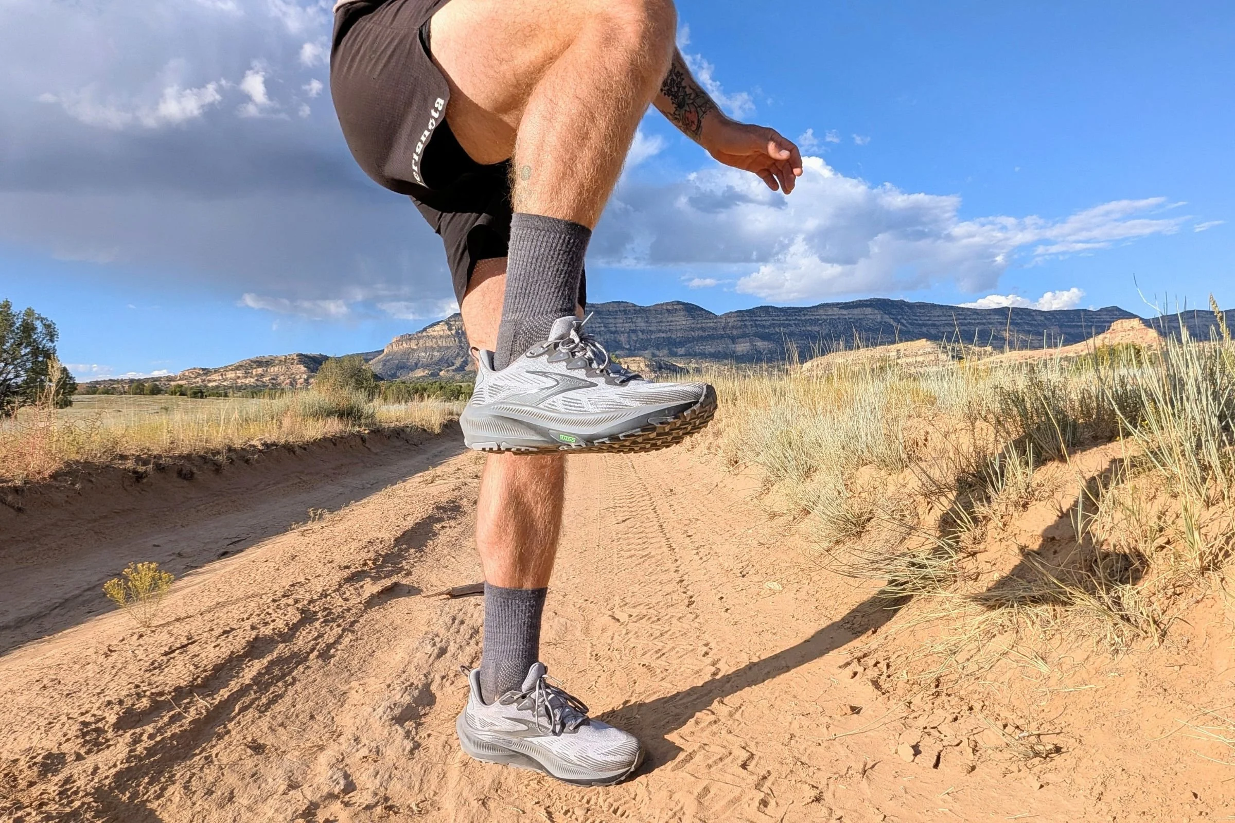 Man wearing Brooks Ghost trail running shoes with one leg lifted.