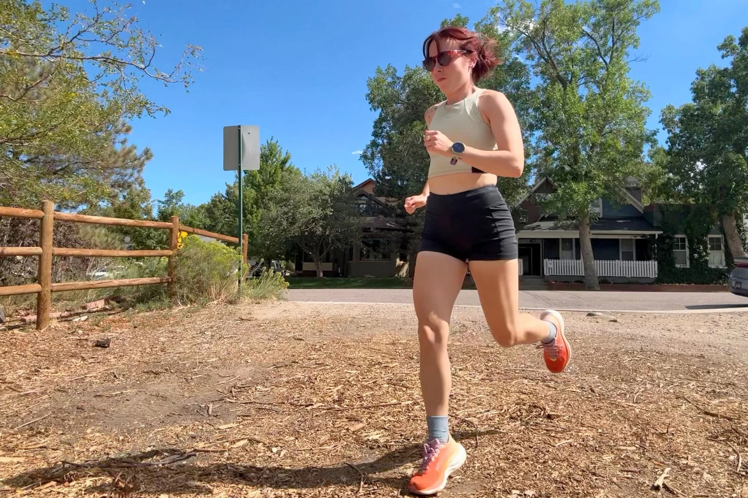 A woman runs along a dirt road wearing Saucony Ride 19 Road Running Shoes and short running tights.