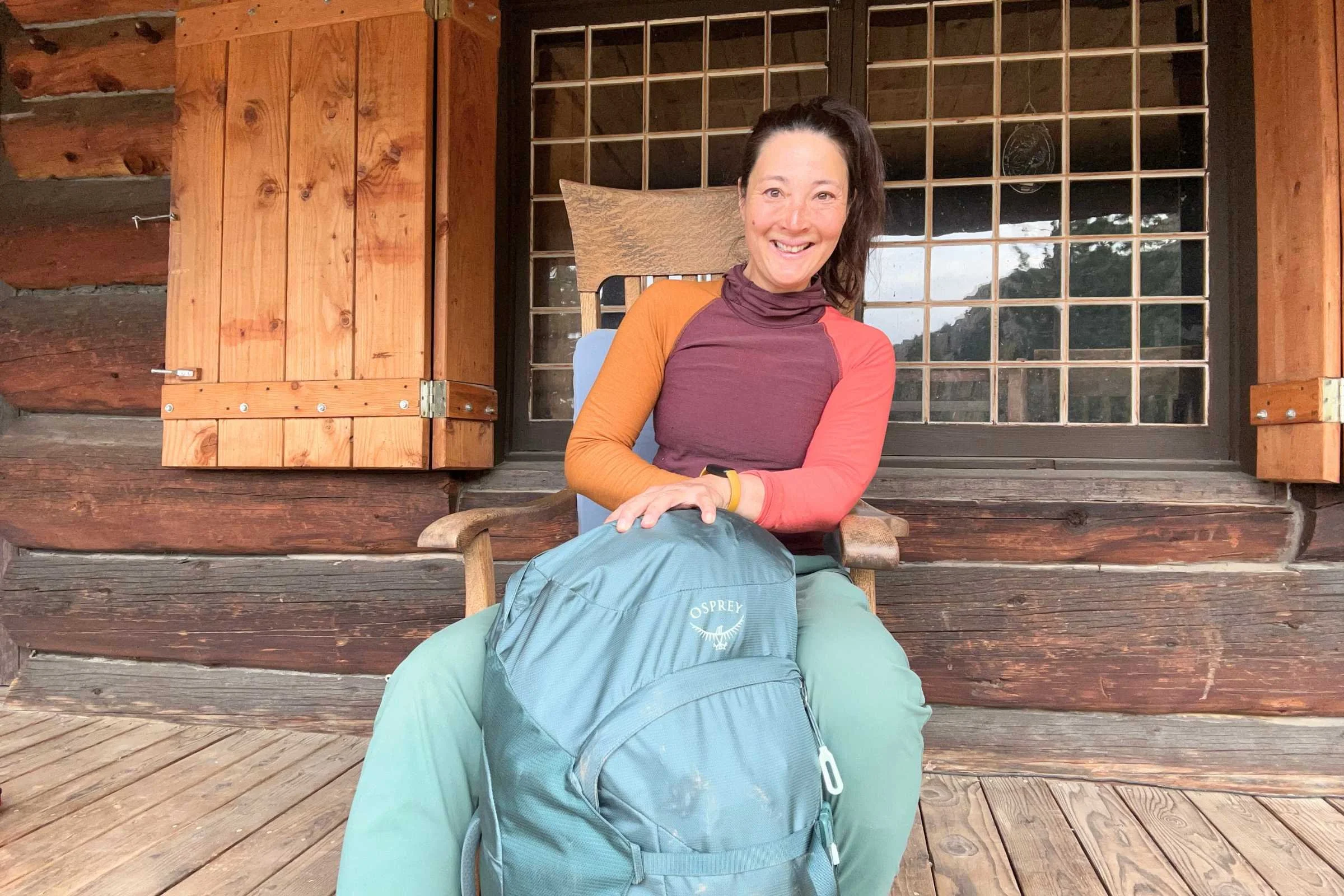 Woman sitting on a porch with the Osprey Fairview Trek 55 Travel Pack beside her.