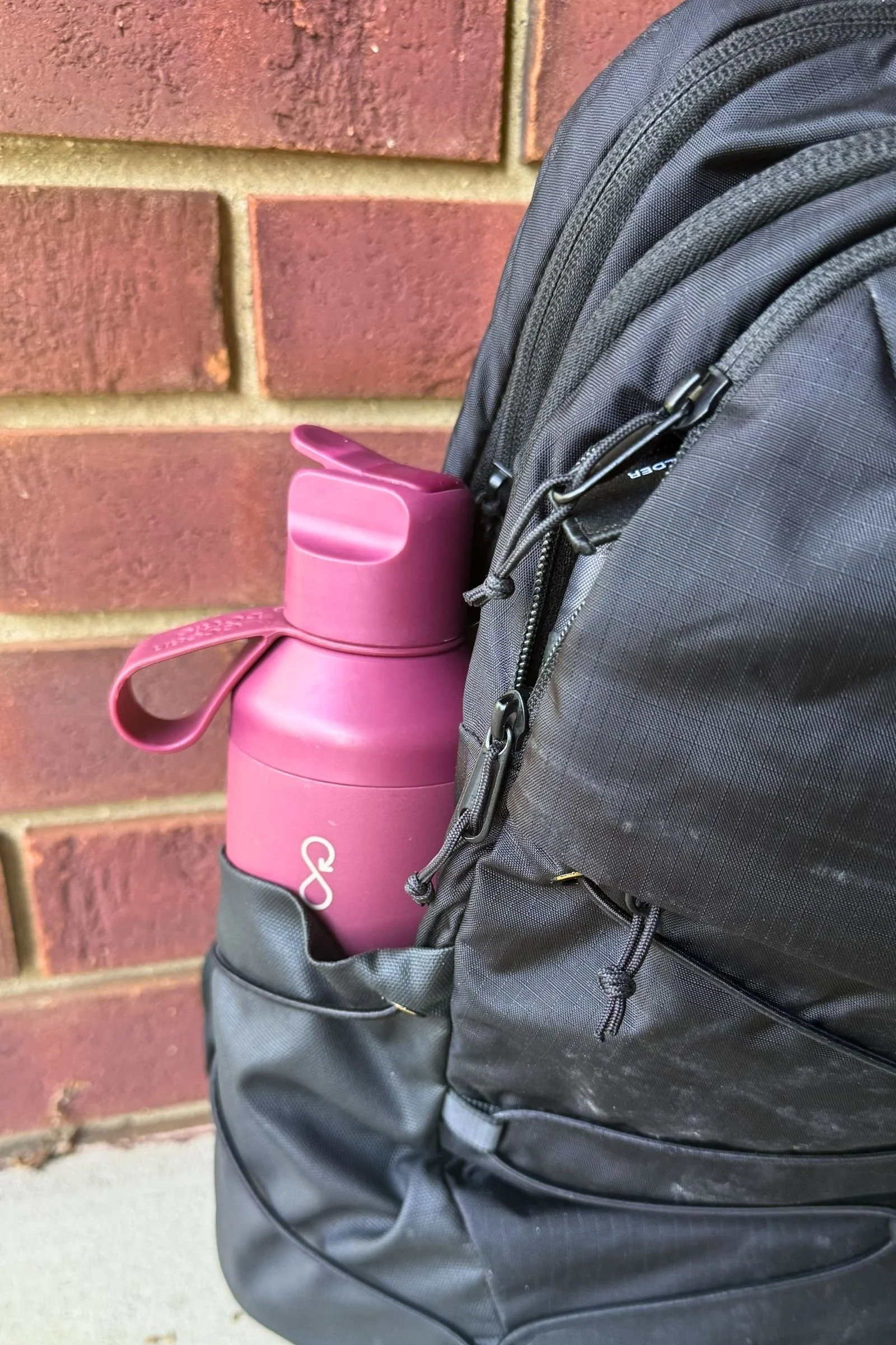 Ocean Bottle Peak Go placed in the side pocket of a backpack, showing its travel-friendly design.