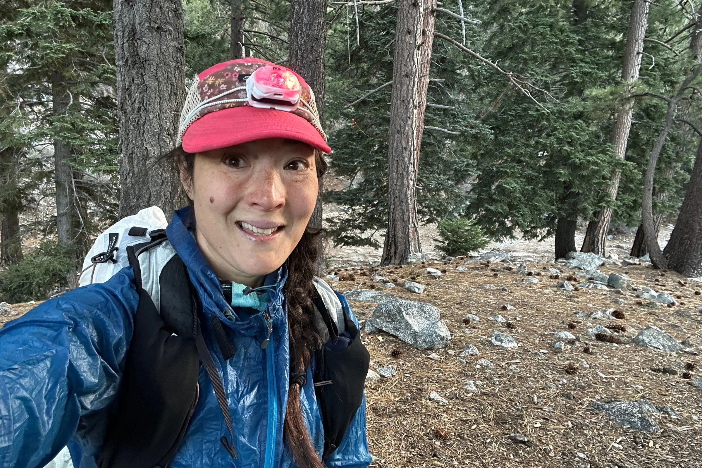 The author wearning the Petzl Swift LT over a red baseball cap, with trees and rocks in the background.