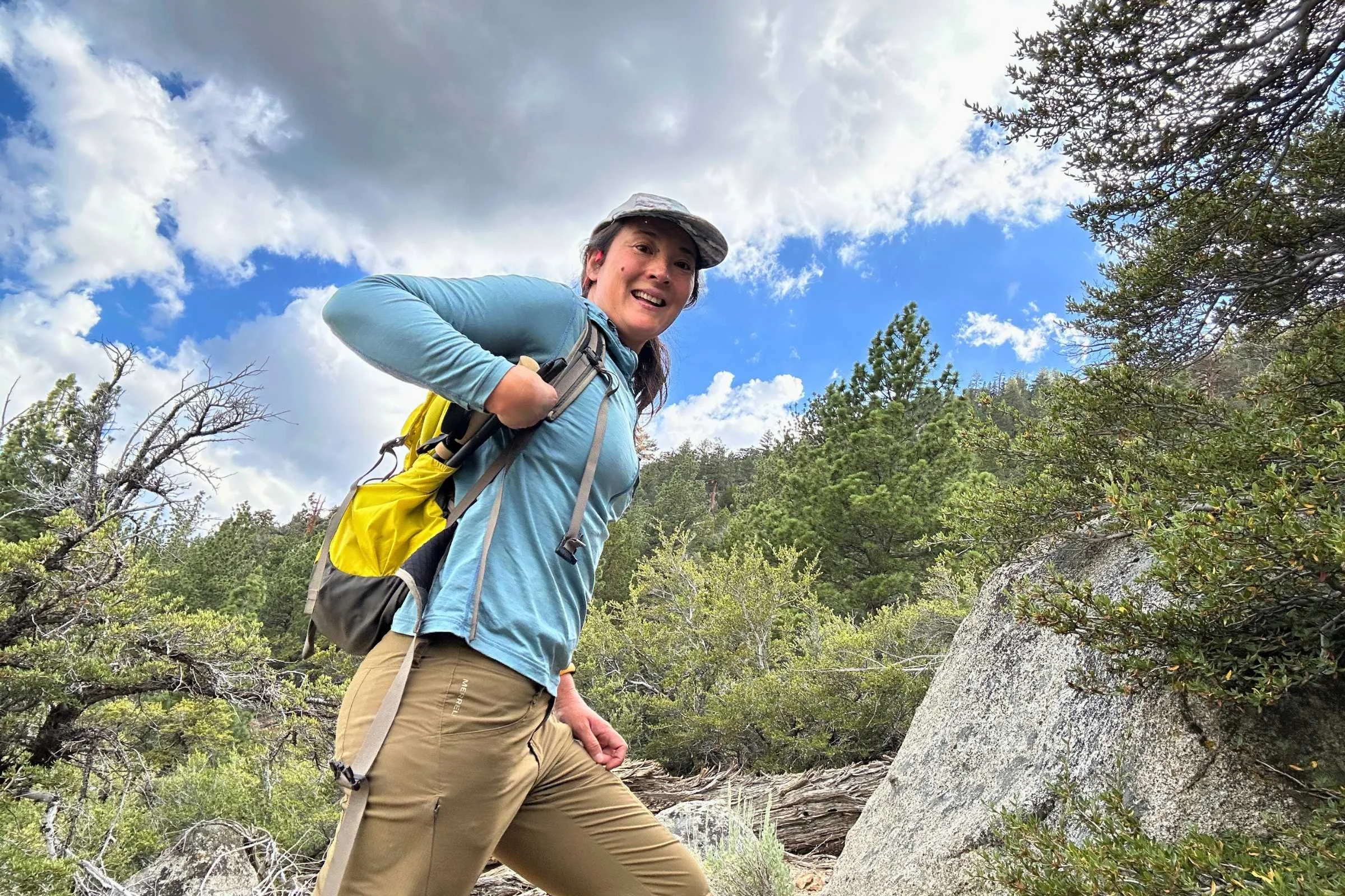 The author removing the Gossamer Gear FT3 poles from her yellow backpack with trees in the background