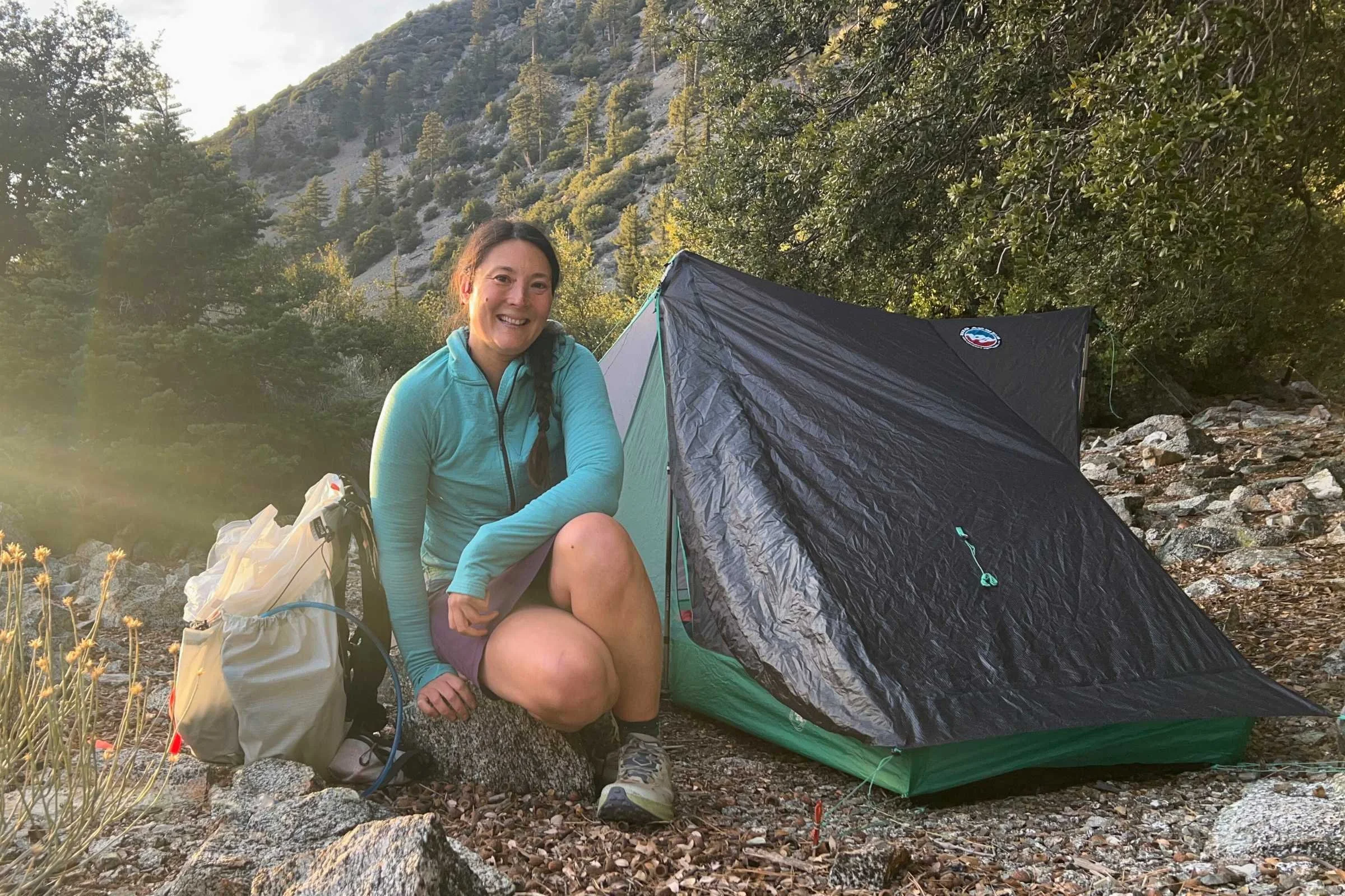Backpacker posing beside Big Agnes String Ridge VST ultralight tent at mountain campsite