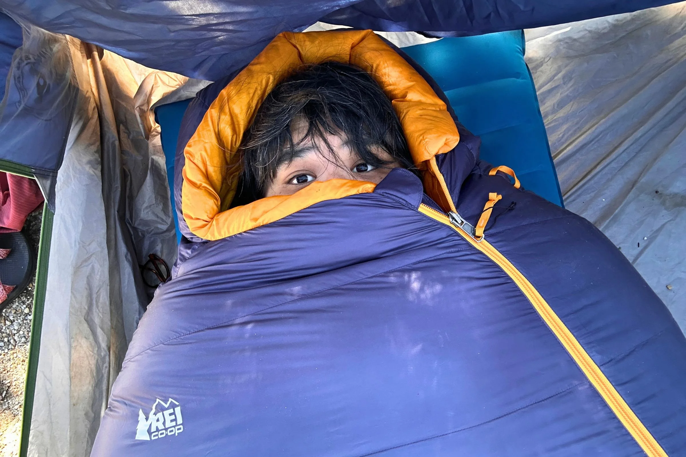 Tester fully zipped into the REI Co-op Magma 30 sleeping bag with just their eyes peeking out.