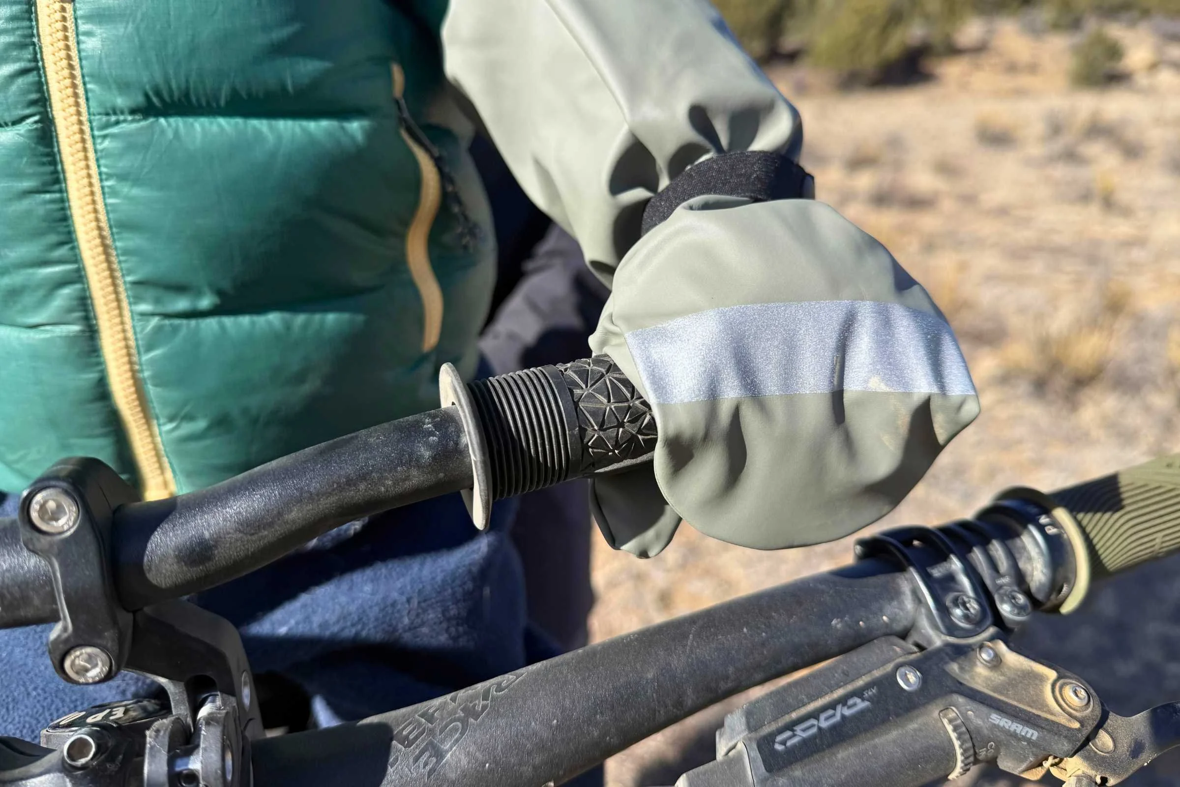 Toddler's hand wearing the Reima Puro waterproof gloves while holding a bike handlebar