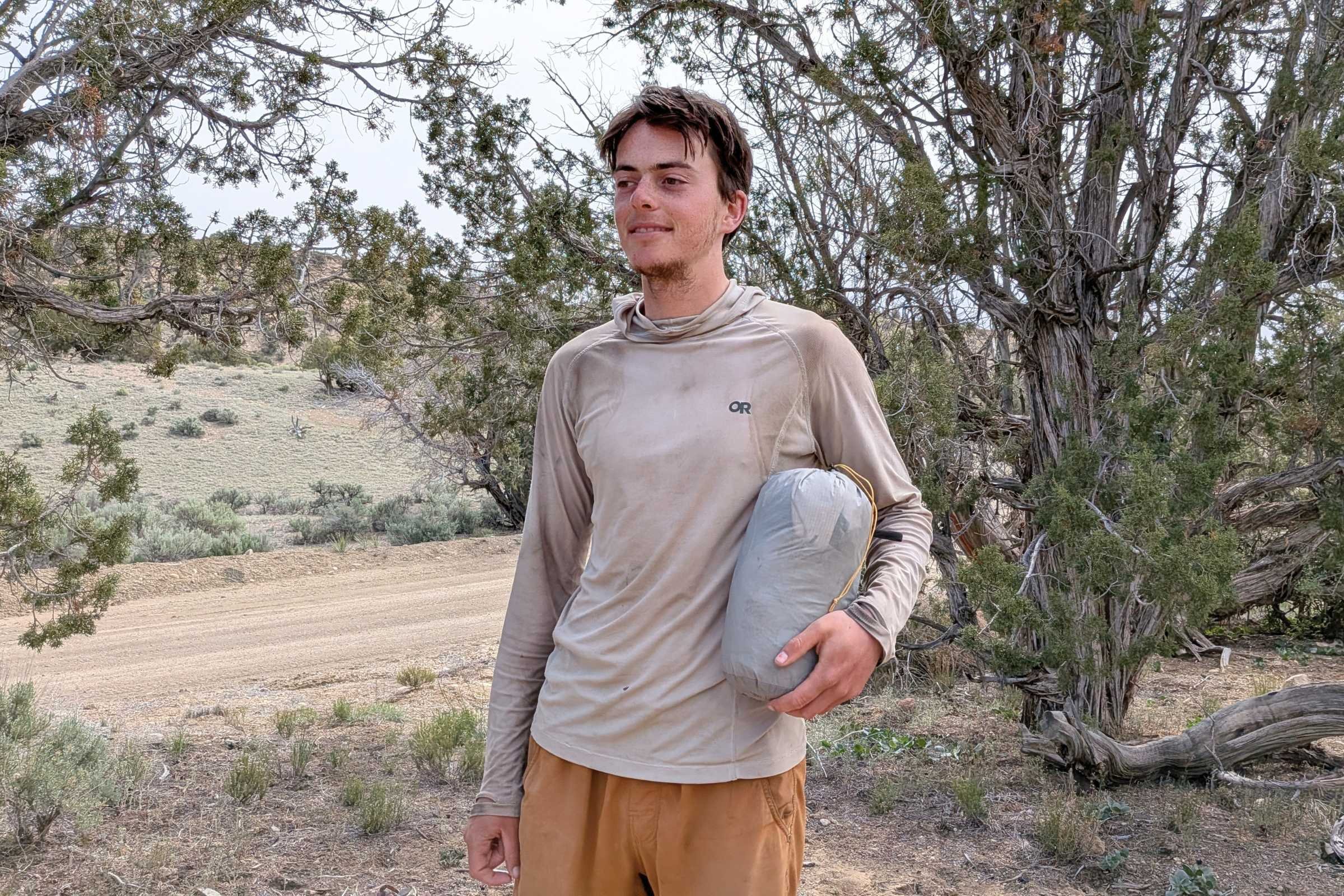 Backpacker in desert holding the folded up Mountain Hardwear Nimbus UL tent