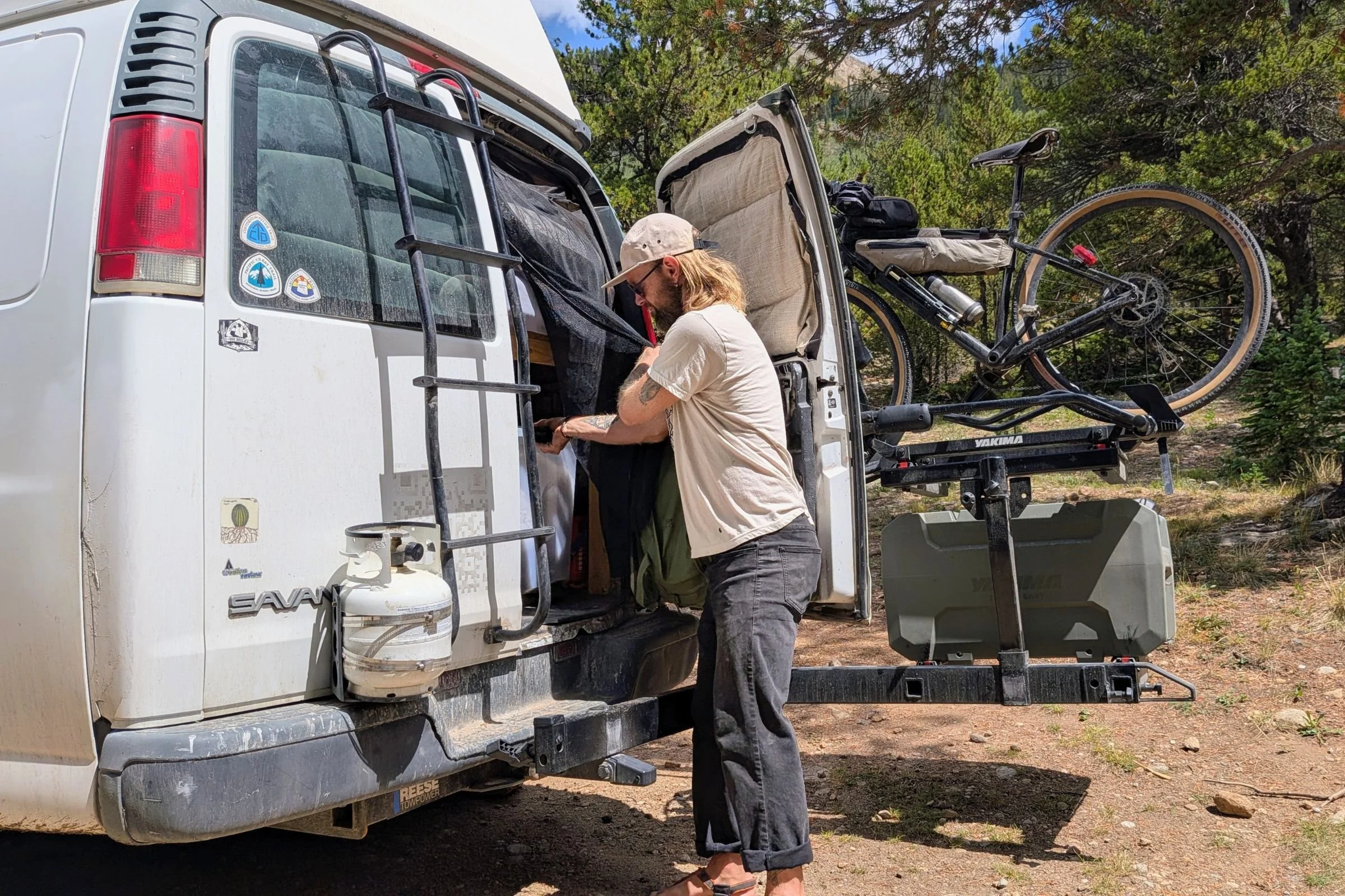A man loads a bike into a van equipped with a Yakima EXO DoubleUp 2-Bike Hitch Rack.