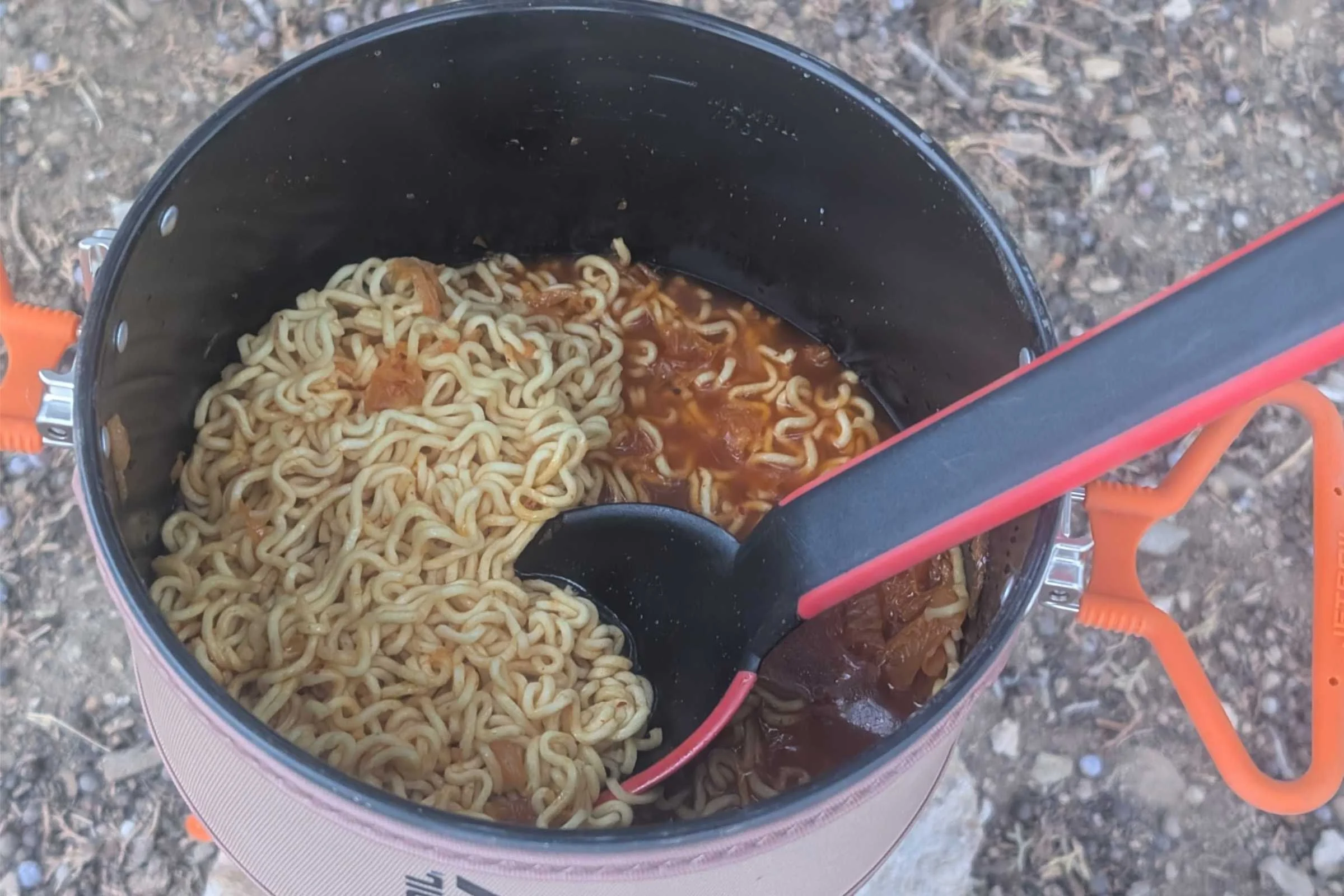A spoon stirs ramen simmering in the Jetboil TrailCook.