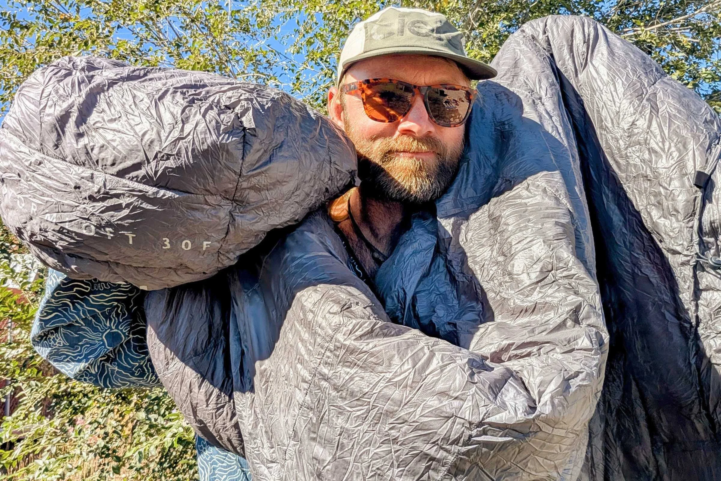 author Sam Schild holds up a gray Outdoor Vitals StormLoft 30 Quilt
