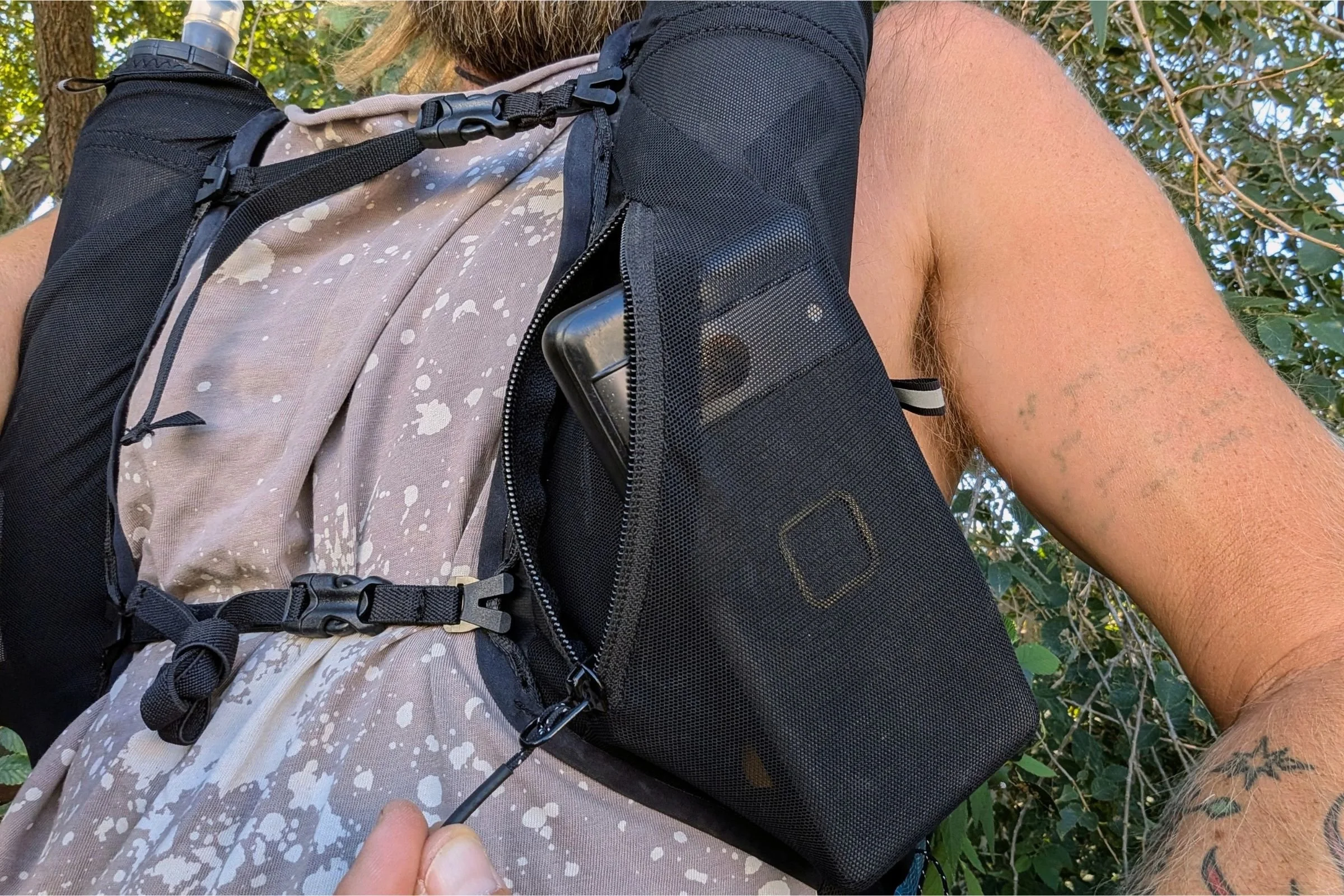 A tattooed man holds the Black Diamond Distance 15 Backpack.