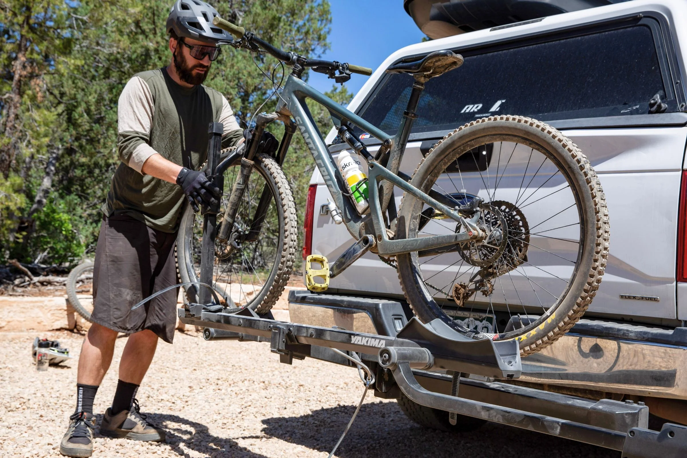 Man loading a bicycle onto the Yakima StepUp Swing 2” Hitch Bike Rack mounted on a trailer.