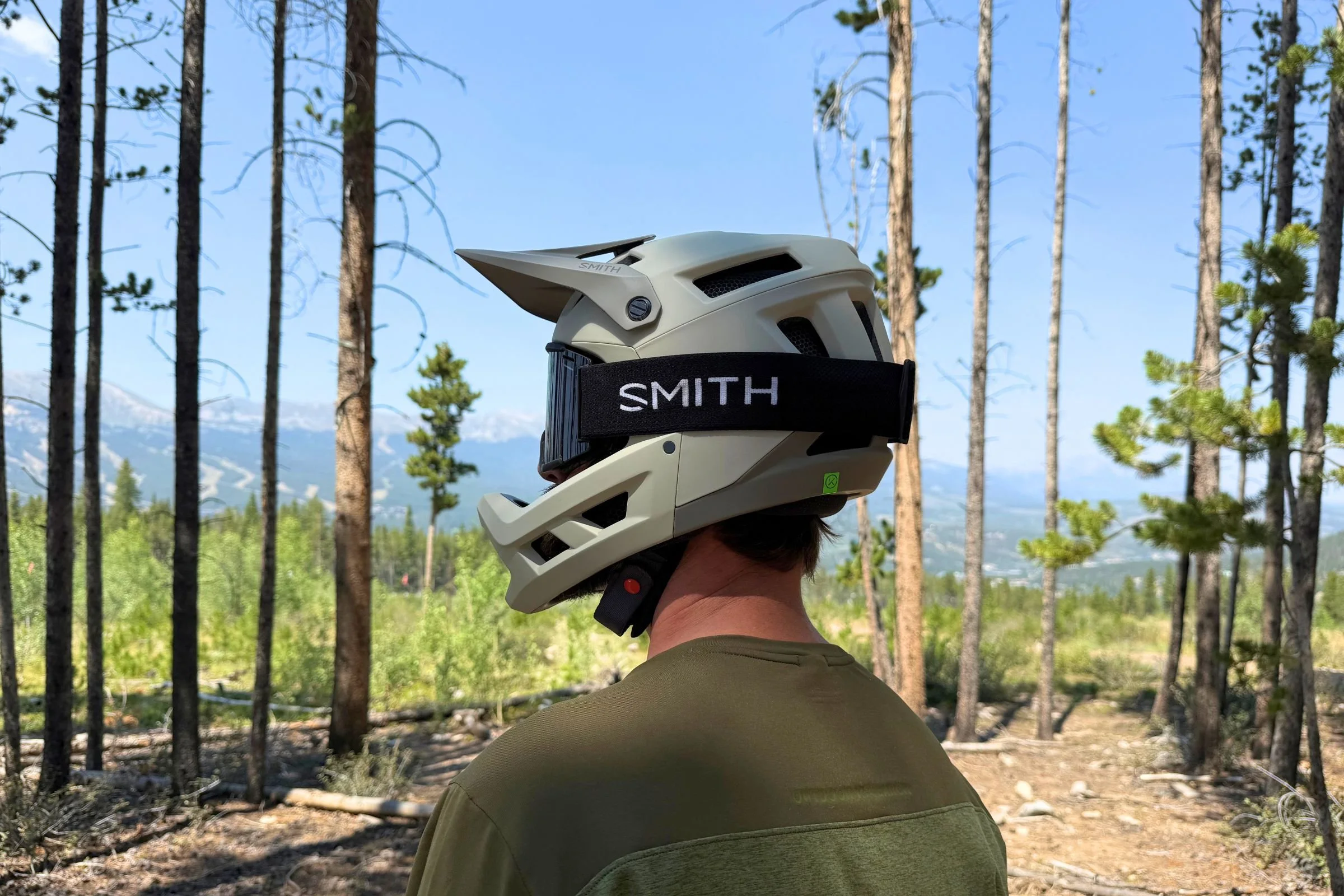 A person wearing Smith Mainline Mips goggles and Smith Mainline Mips stands among trees in the woods.