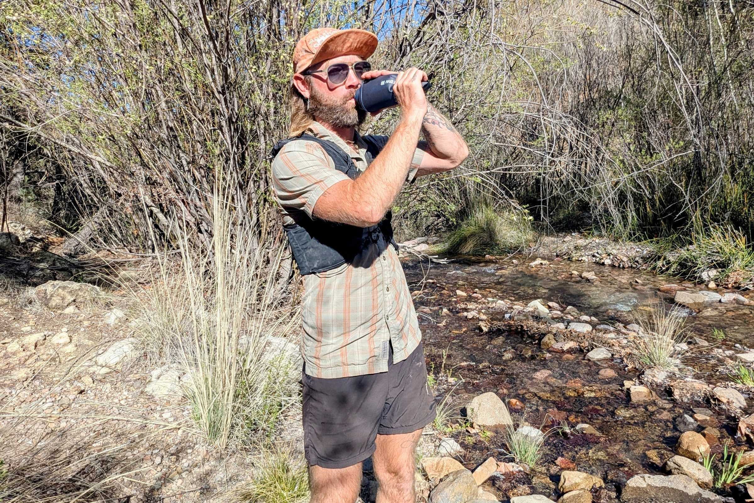 Hiker drinking from LifeStraw Peak Squeeze by a flowing stream