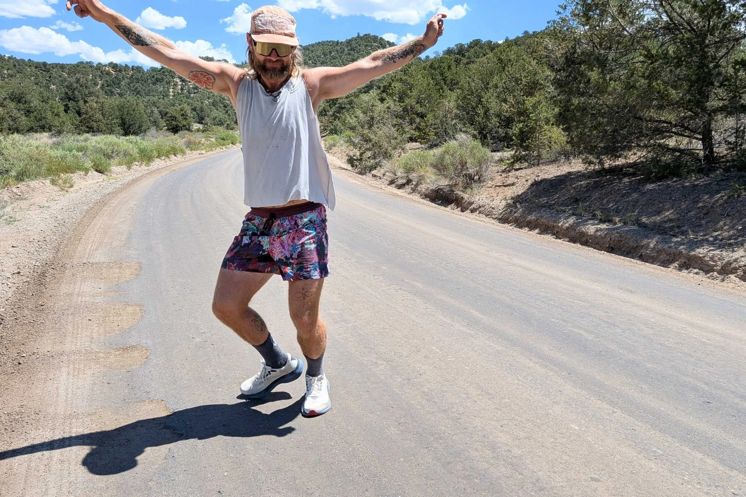 A man wearing Janji AFO Middle Running Shorts jumps on a road.