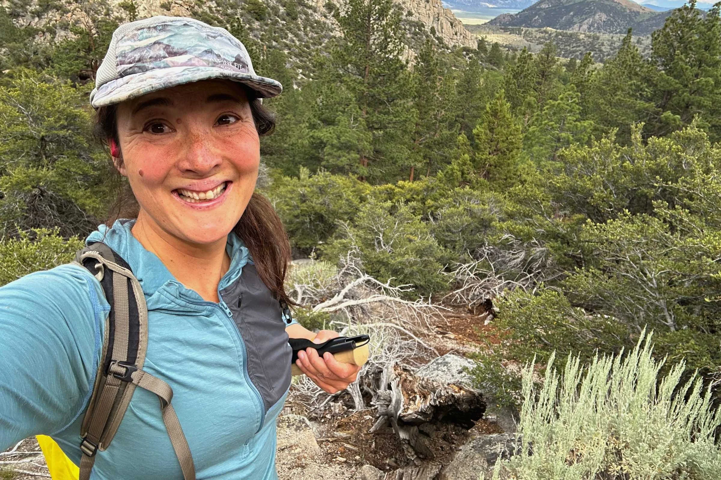 The author on a hike, with mountains and trees in the background.