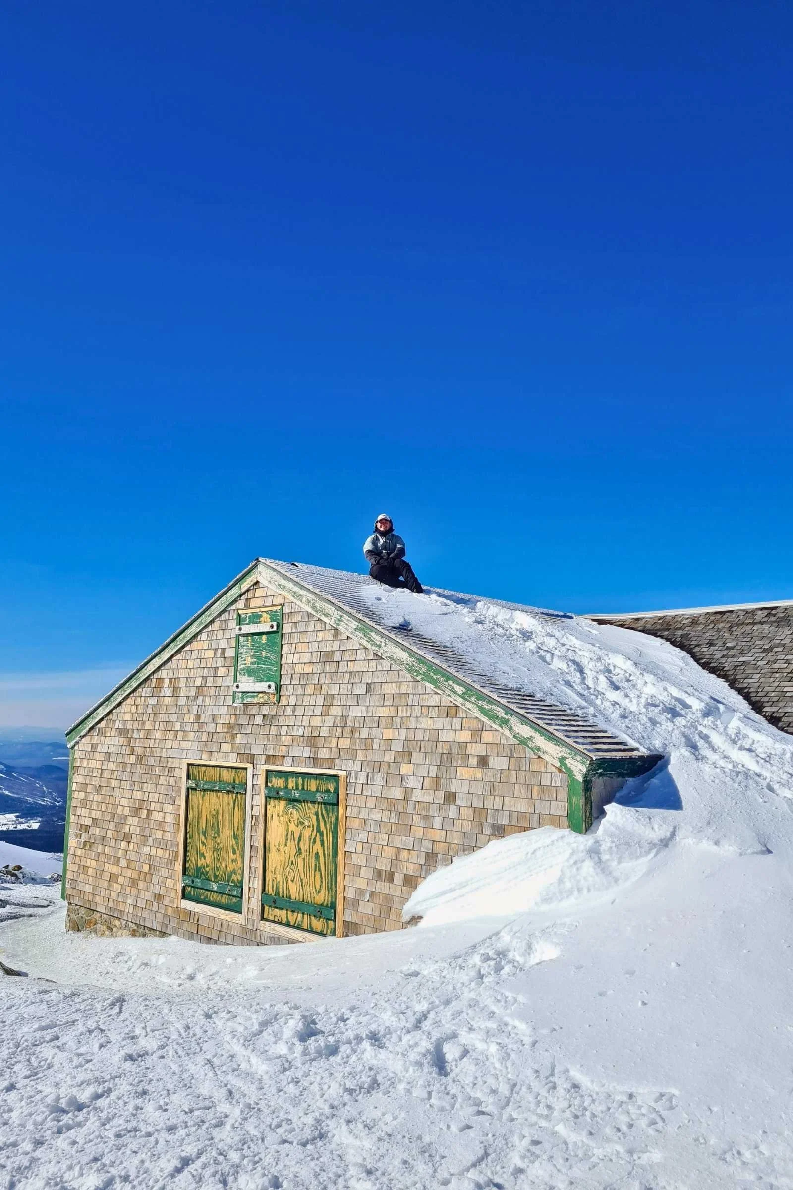 The author sitting on the roof of Lake of the Clouds hut in February. Photo by Matt.
