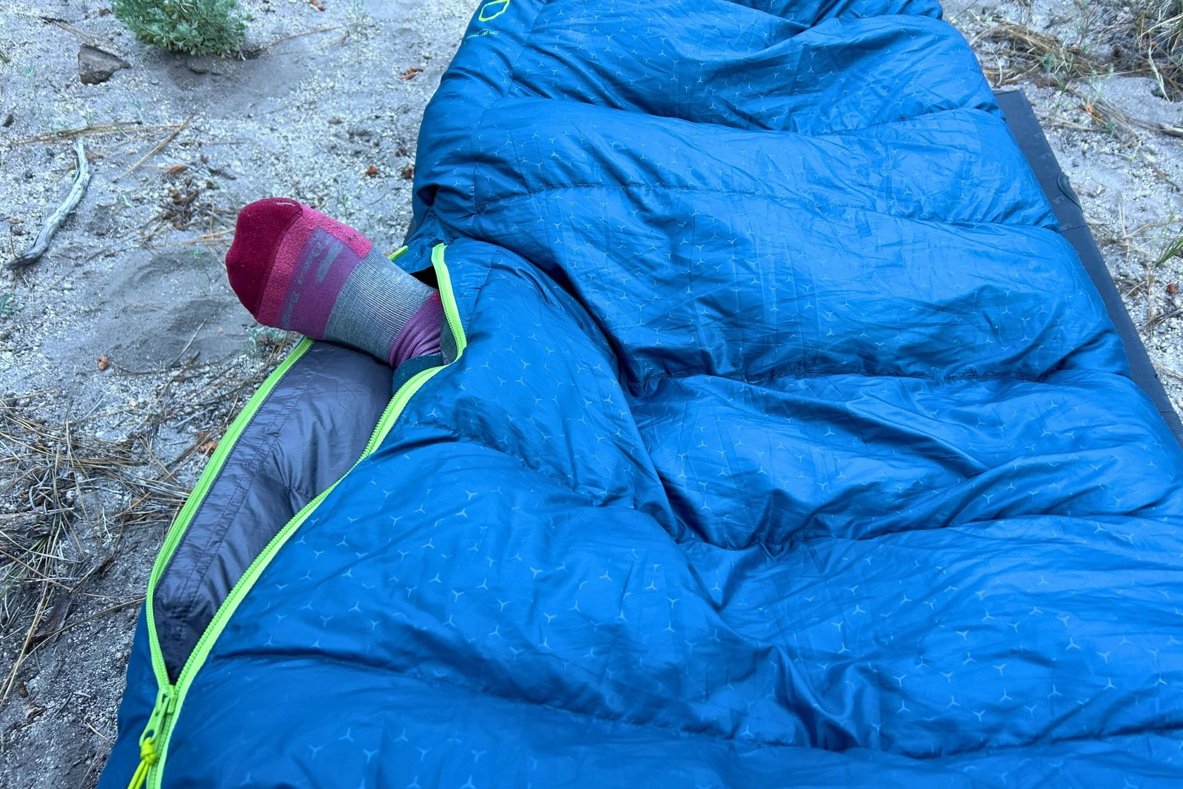 An Exped Terra Sleeping Bag with the zipper partially open and a peron's foot sticking out.