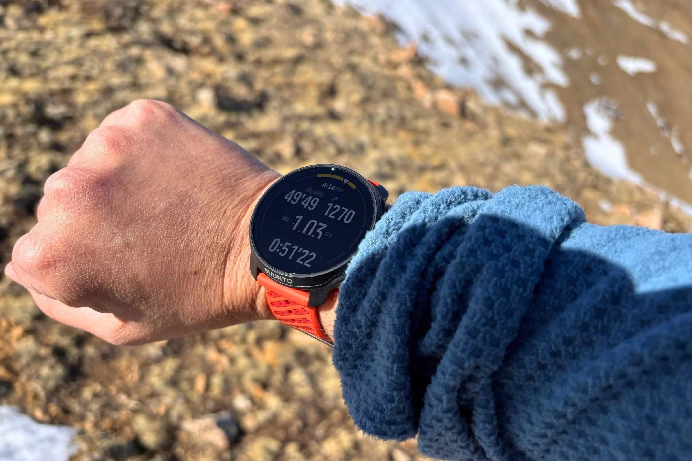 The Suunto Race 2 GPS watch with a snowy peak in the background..