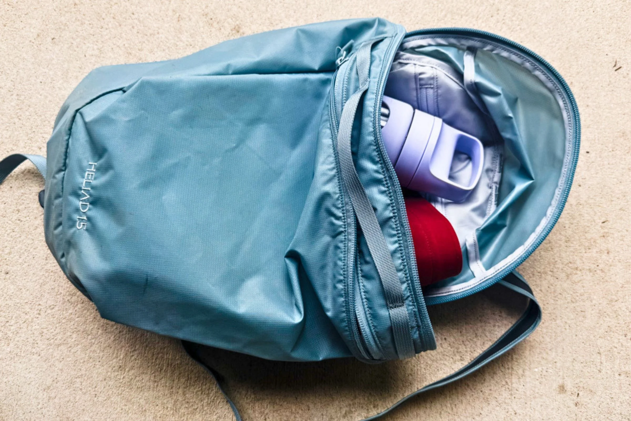 Arc’teryx Heliad 15 backpack with its main compartment open and a water bottle inside.