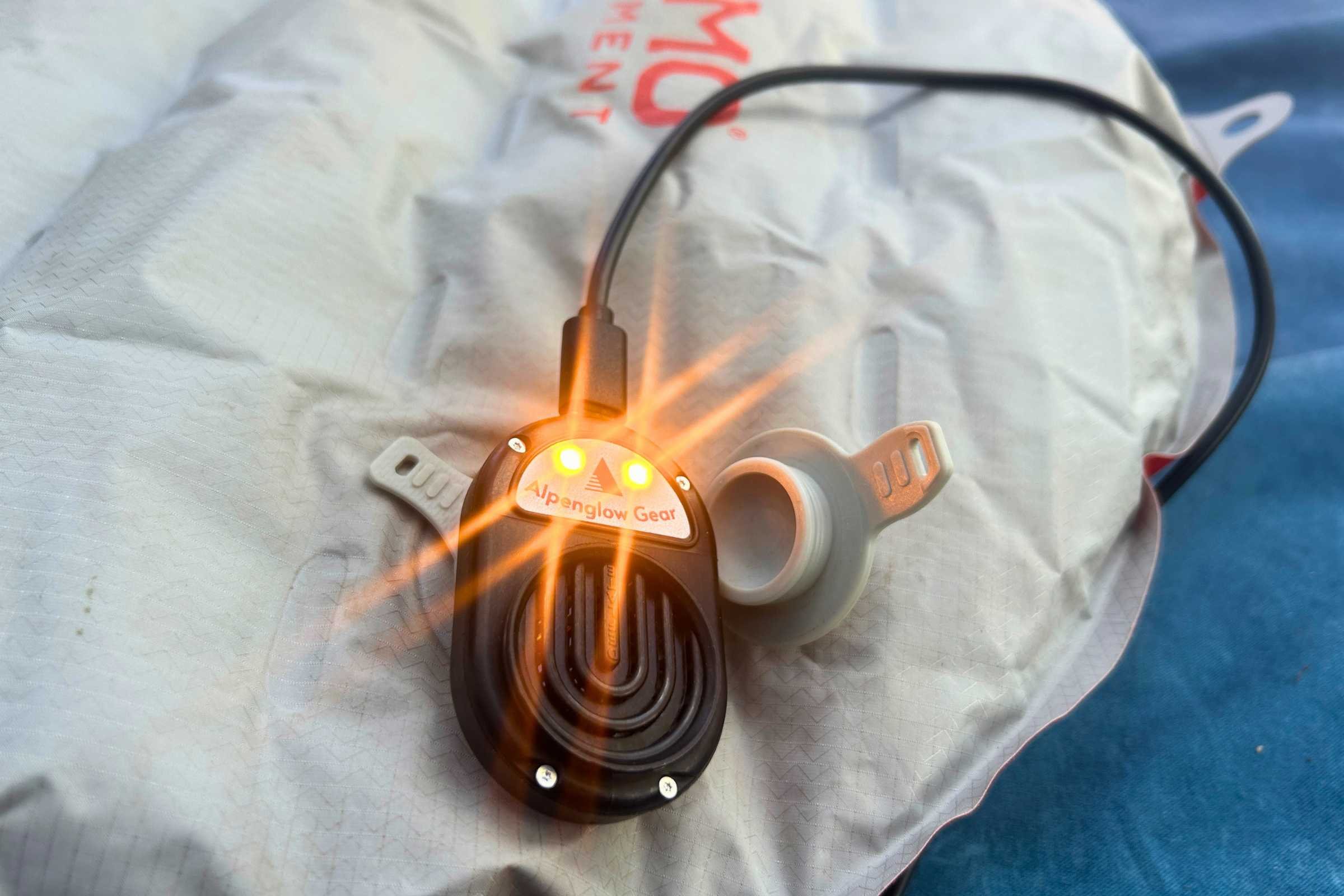 Alpenblow Lux flashlight attached to a sleeping bag in an outdoor camping scene.