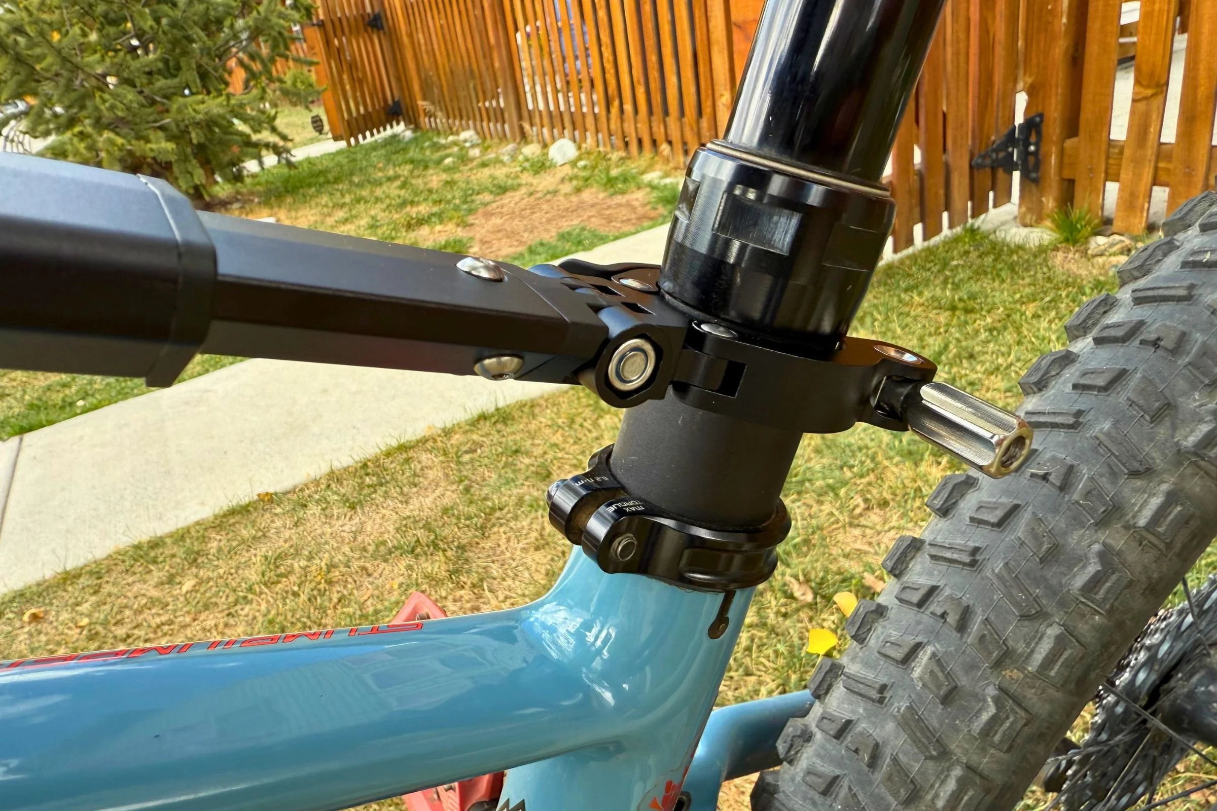 A closeup of the stem attachment on the  Kids Ride Shotgun Shotgun Pro EVO 2-in-1 bike seat, as attached to a blue mountain bike.
