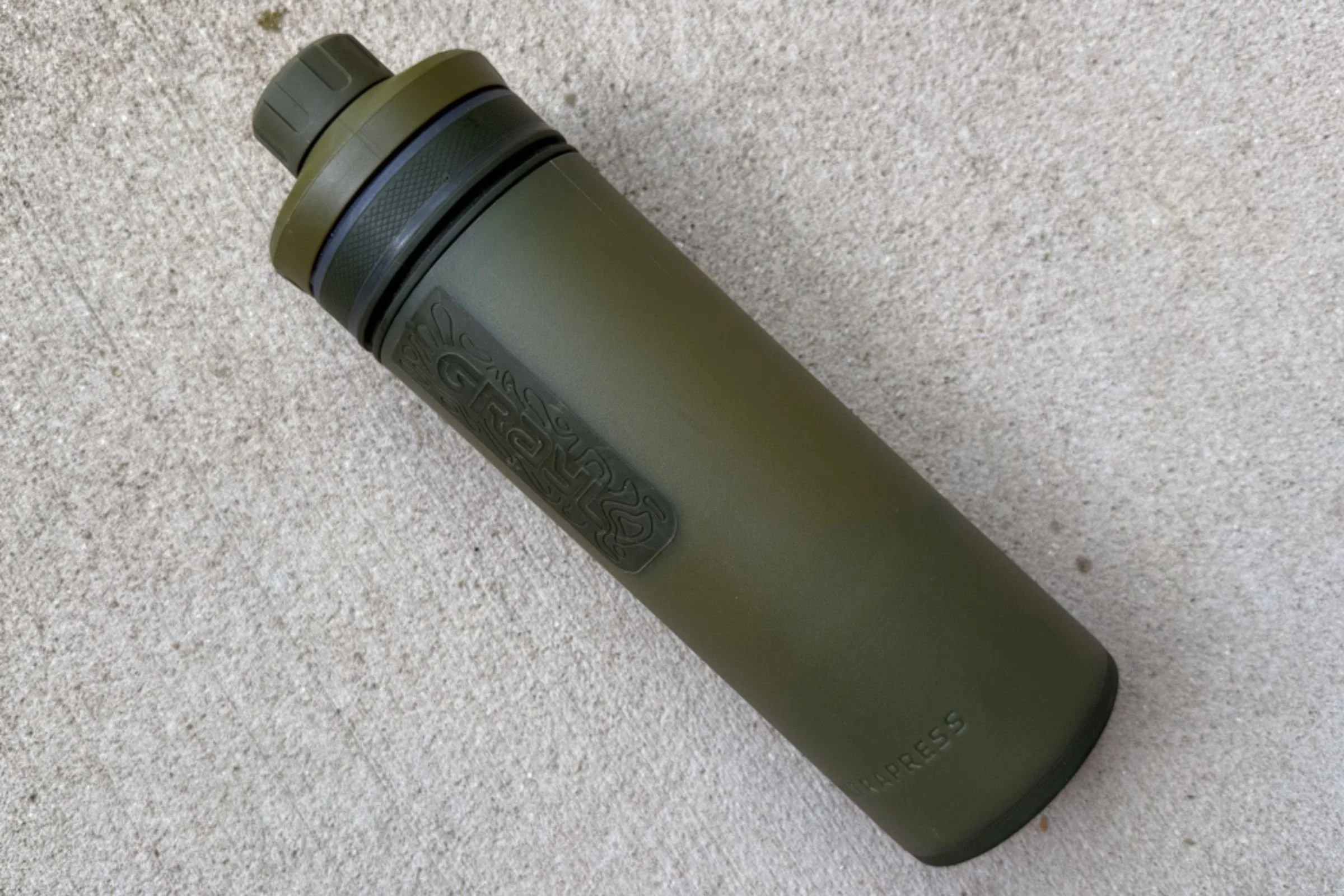 Grayl UltraPress Filter and Purifier Bottle resting on a textured concrete surface