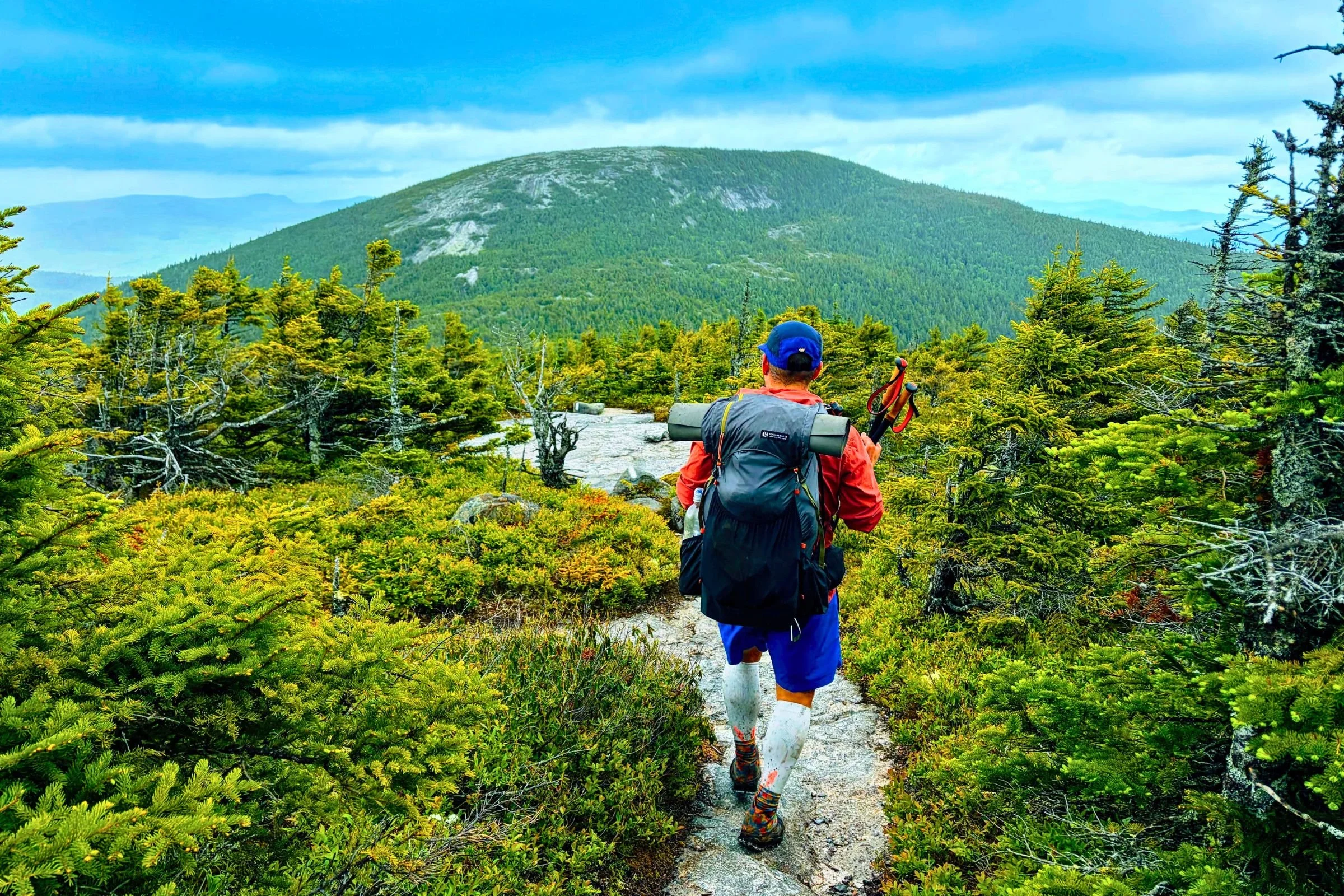Backpacker on a rocky section of the Grafton Loop Trail, with a mountain ahead.