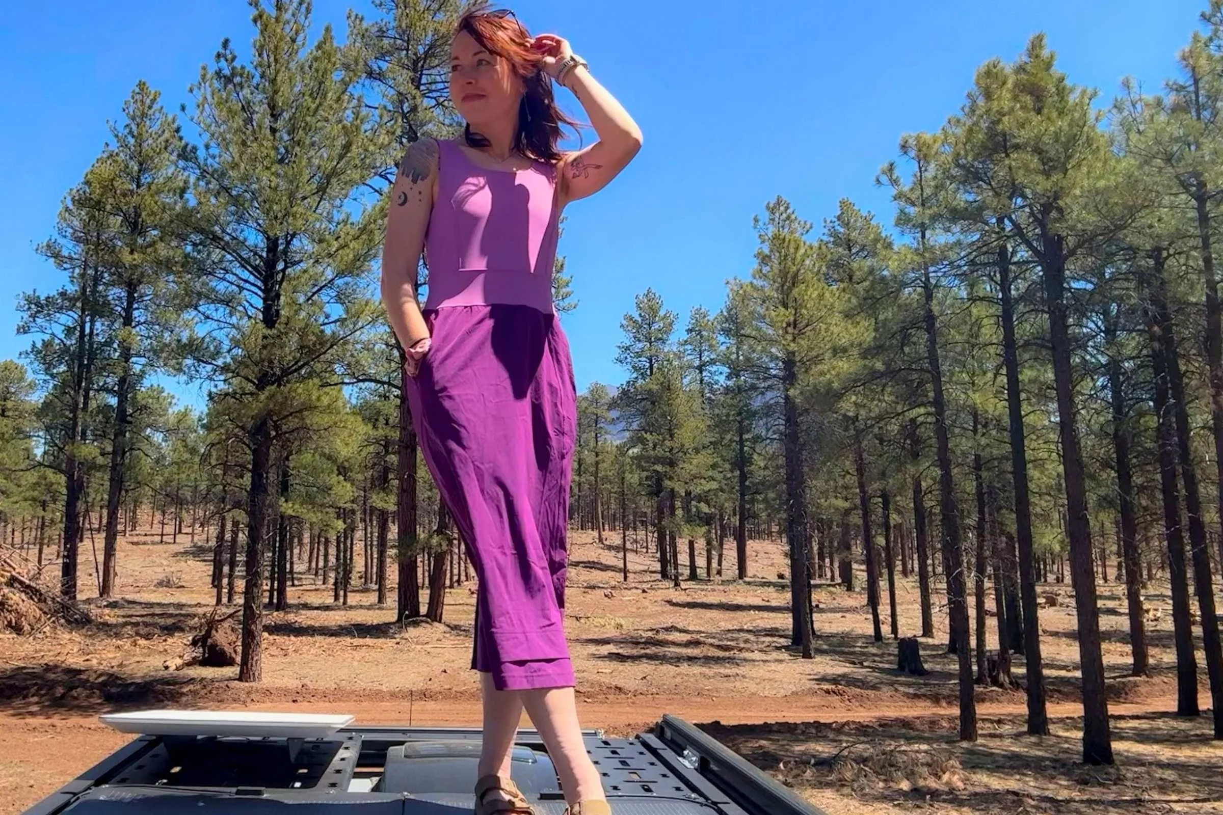 Woman posing on top of a campervan with a pine forest in the background wearing the Title Nine Limitless Midi Dress