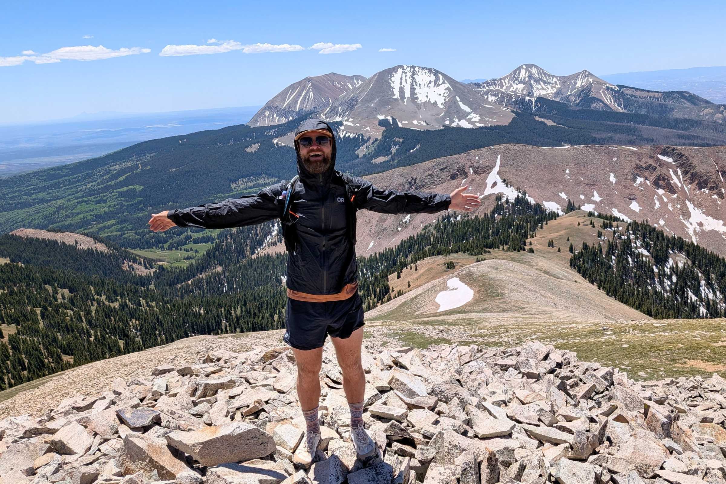Author Sam Schild stands on a mountain ridge wearing the Outdoor Research Helium UL Jacket