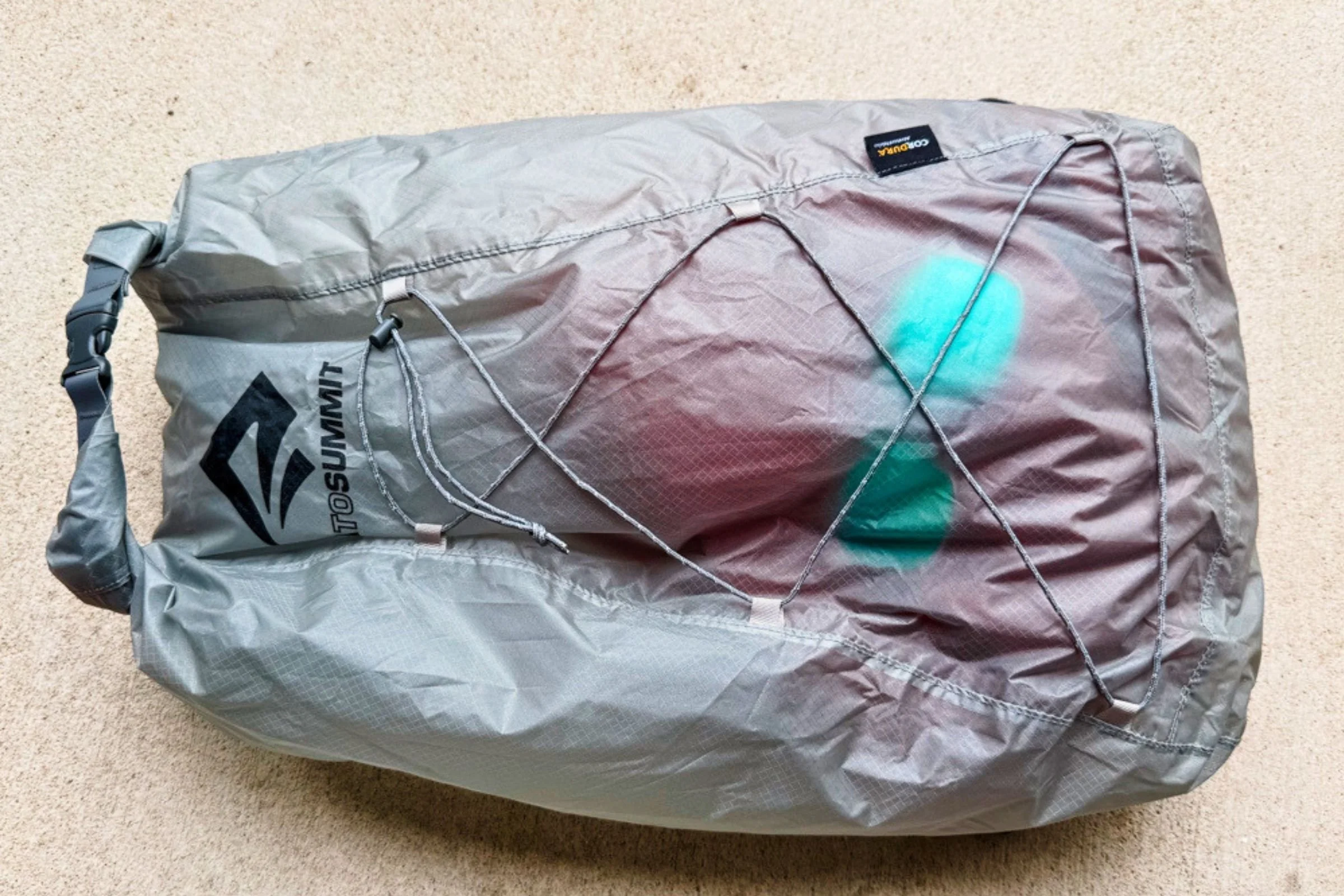 Sea to Summit Ultra-Sil Dry Daypack filled with gear, with contents visible through its gray fabric.