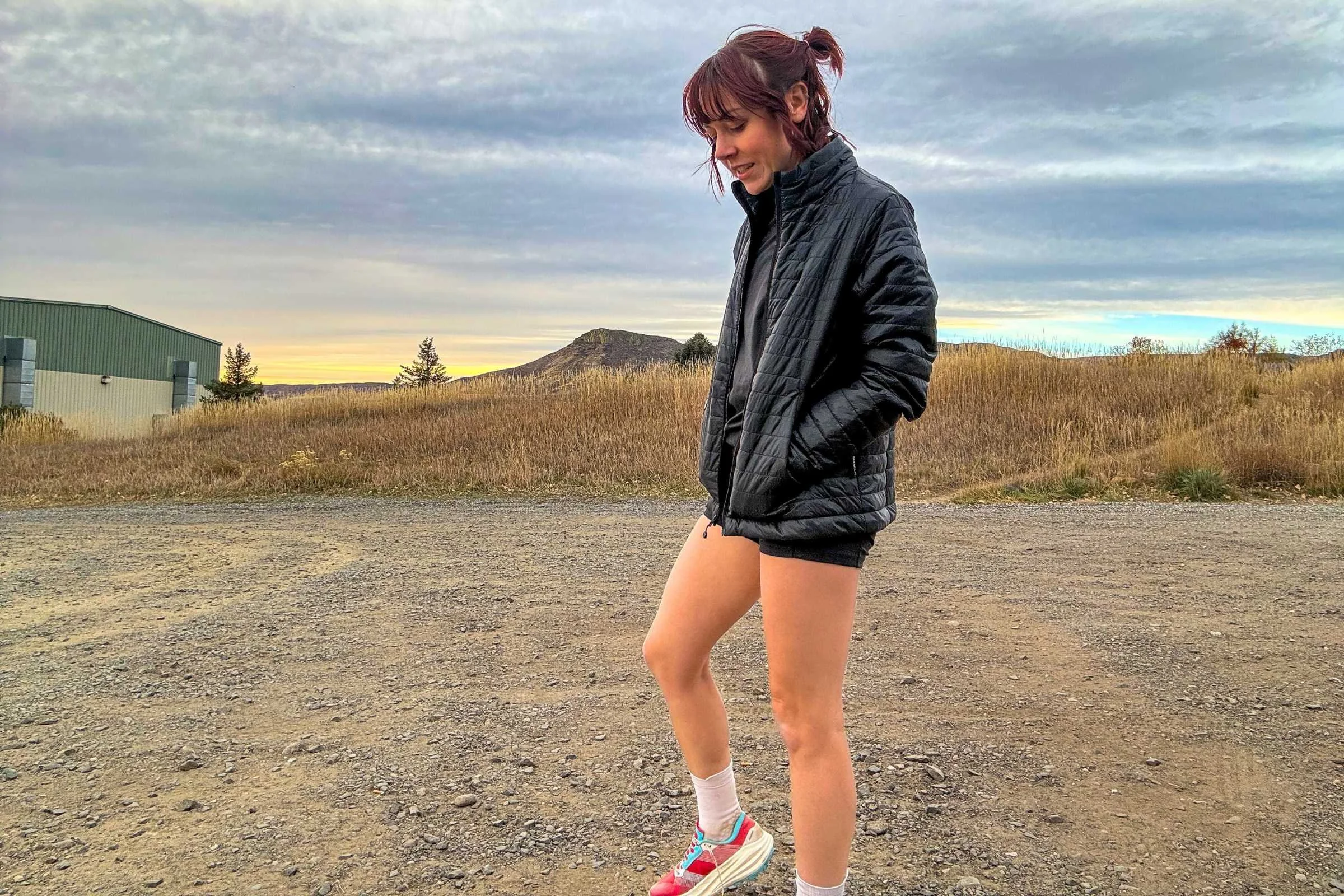 person walking in a gravel parking lot wearing a black PAKA Mayu Ultralight jacket