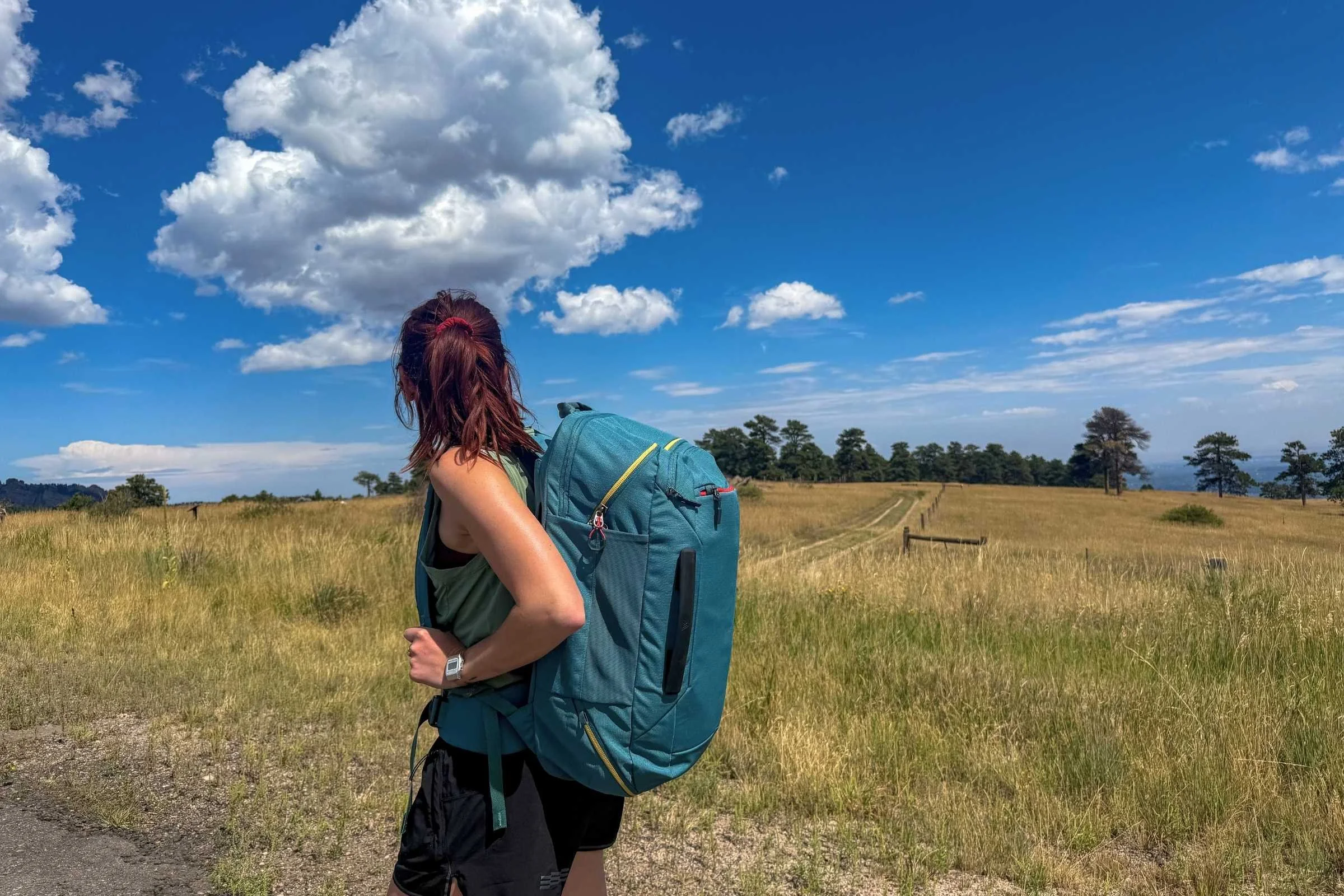 Tester walking along a open field carrying the Gregory Border Carry-on 40