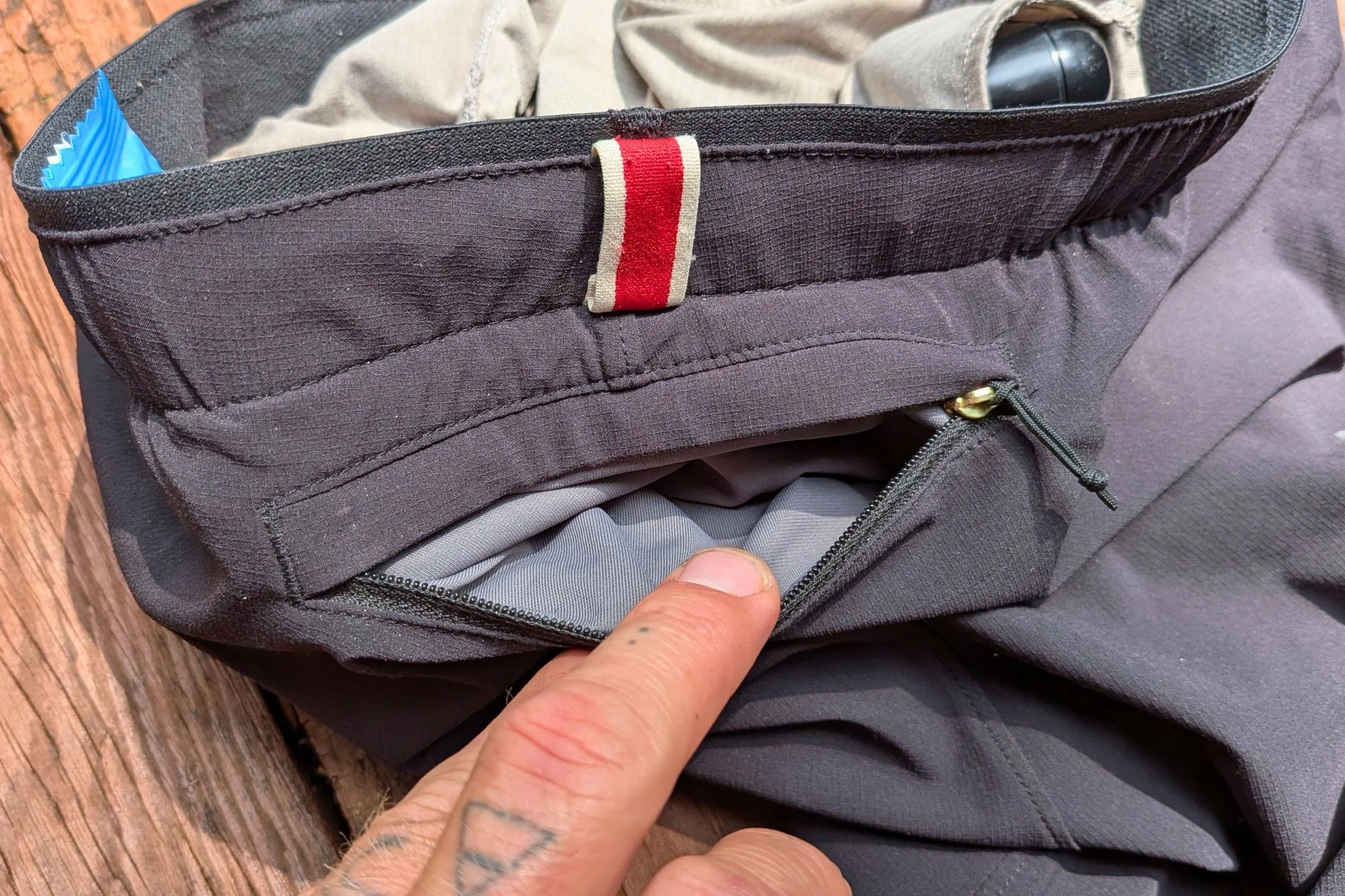 Close-up of a hand holding the pocket of Tracksmith Twilight Running Shorts.