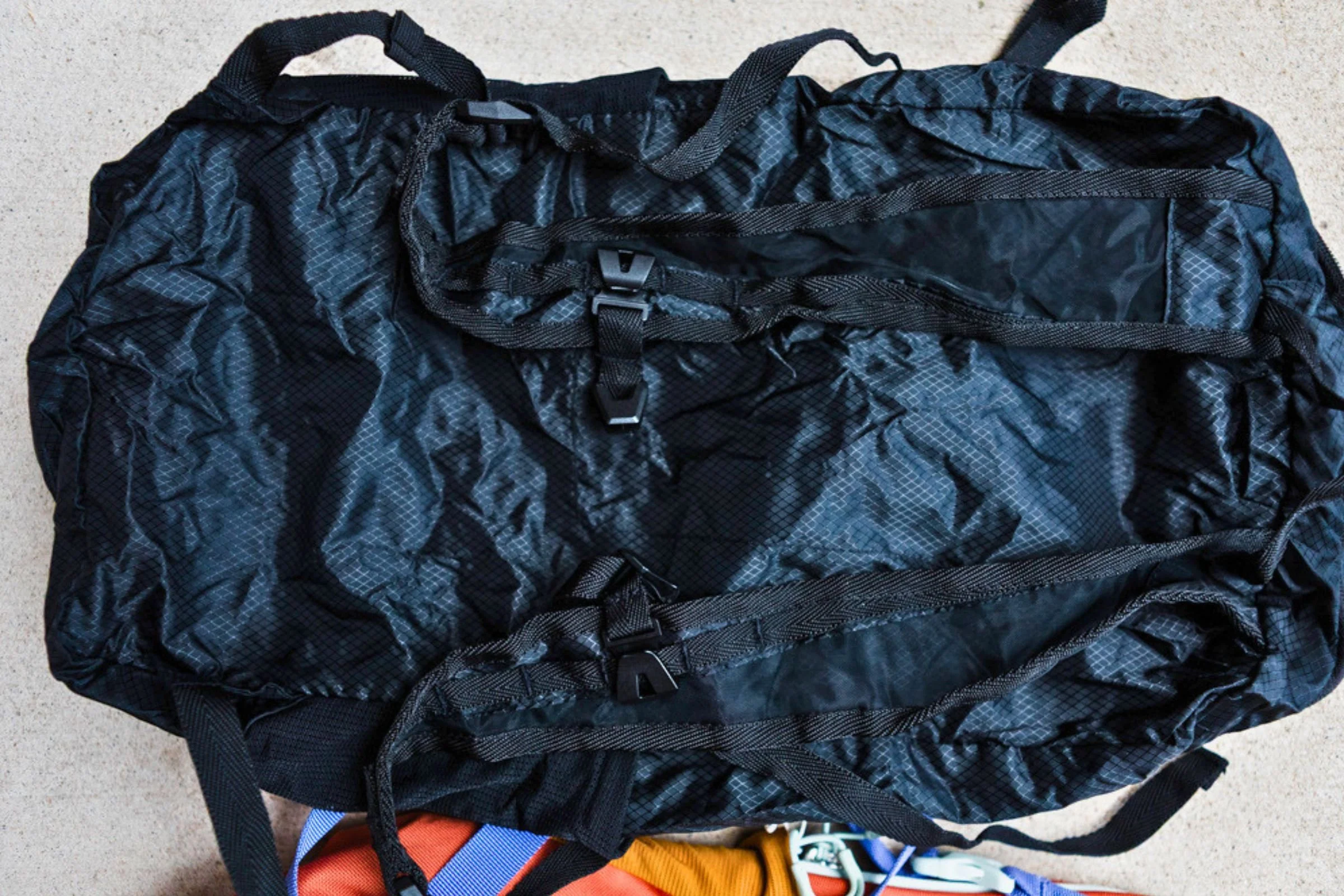 Black Eagle Creek Packable Backpack shown with its shoulder straps visible among travel items.