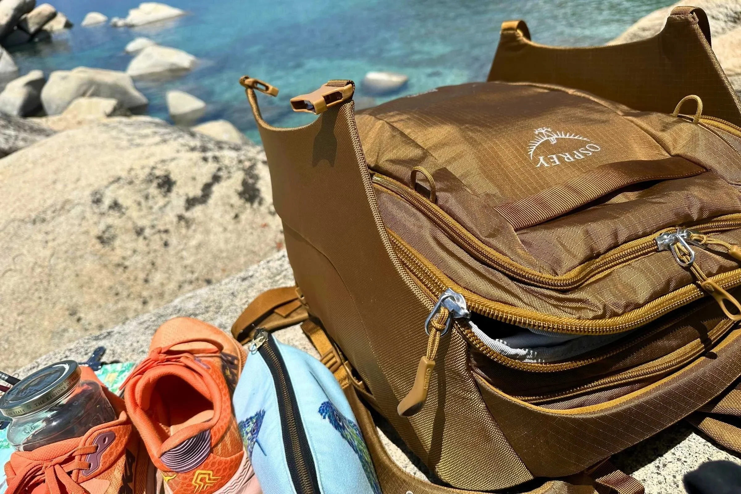The Osprey Sojourn Porter 46 travel pack next to a sparkling blue lake