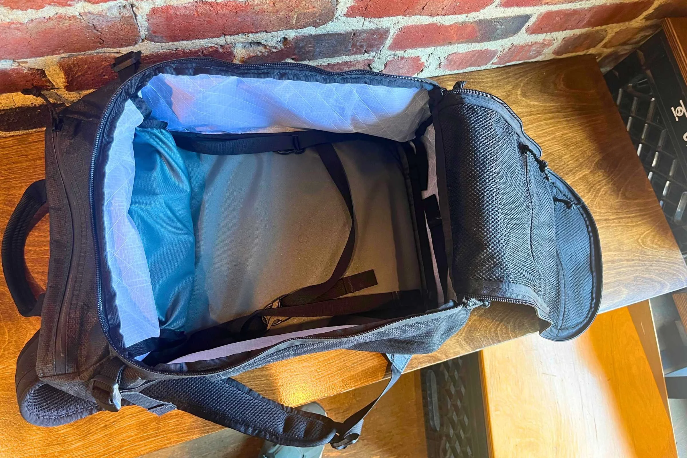 ULA Ultra Dragonfly 30L Adventure Travel Backpack close up, showing organization pockets and a blue-and-black zipper.